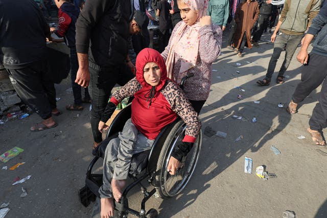 <p>A Palestinian woman in a wheelchair, as people shop at a market, amid the war</p>
