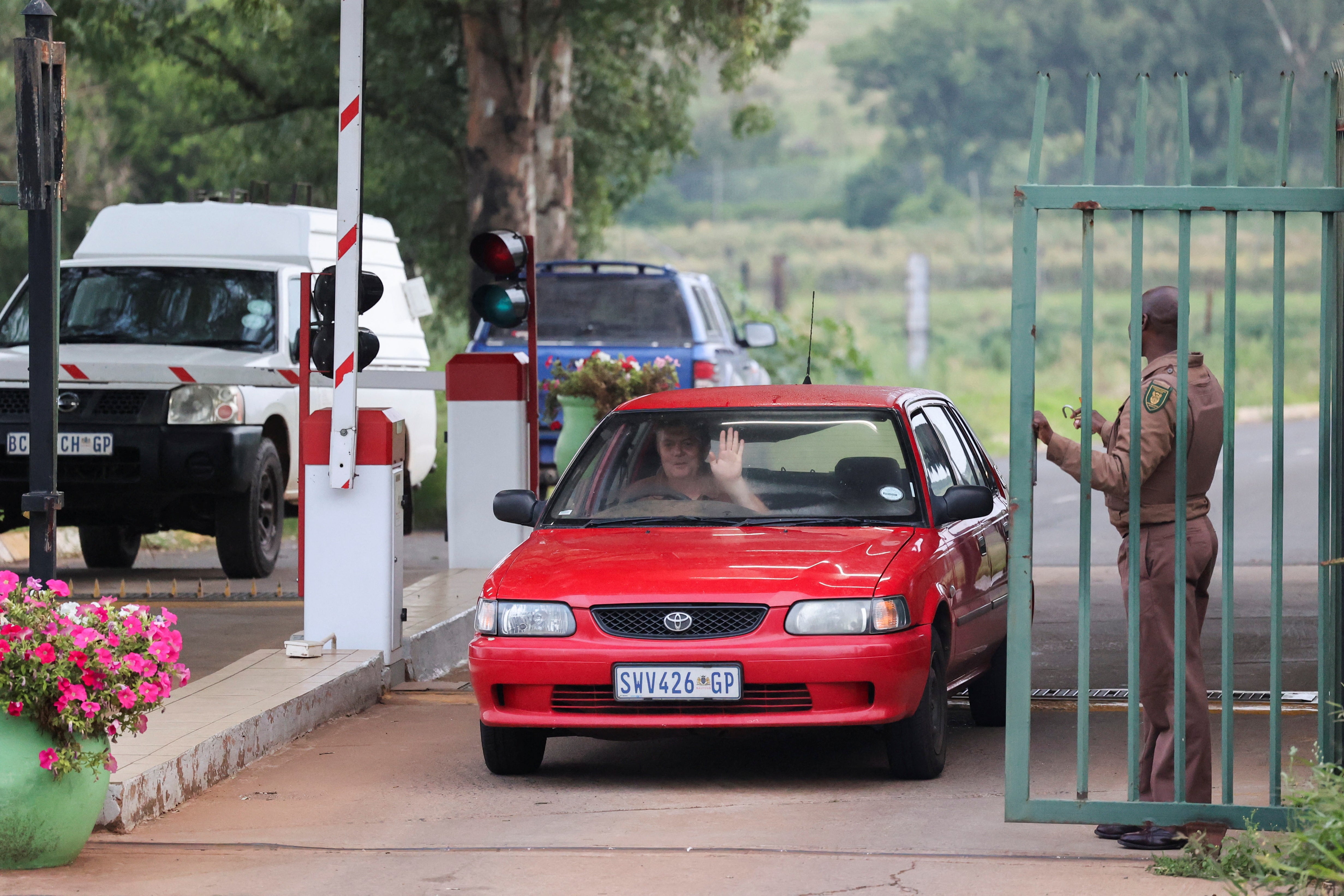 A car drives past the gates as a Correctional Services officer stands guard at the entrance of the Atteridgeville Correctional Centre, where South African athlete Oscar Pistorius, convicted of killing his girlfriend Reeva Steenkamp in 2013, is due to be released on parole, in Pretoria, South Africa