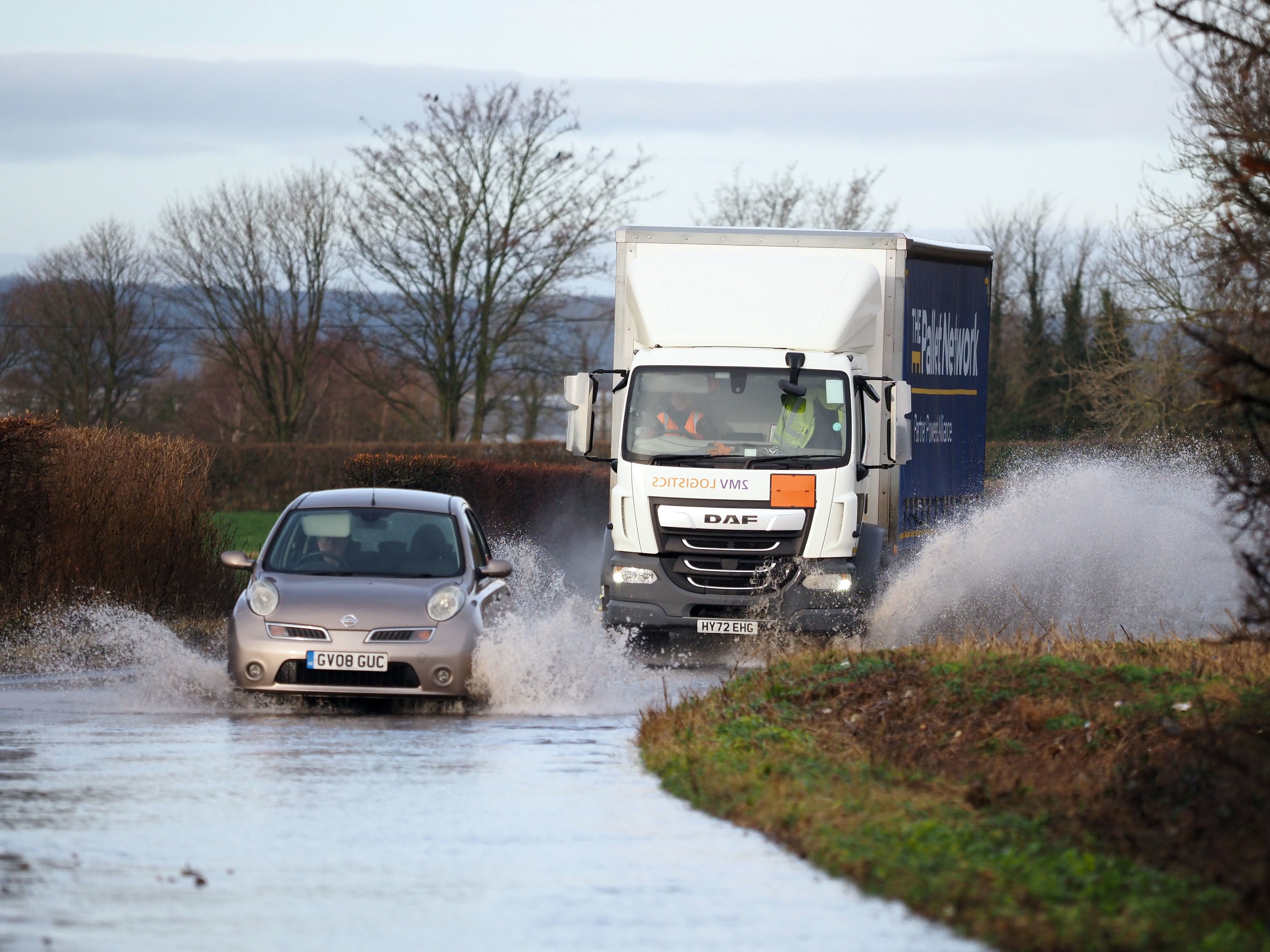 Vehicles driven through a flooded road in Aldingbourne, West Sussex last week