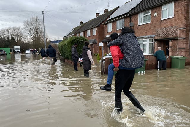 <p>Residents wade through flood water in Loughborough, Leicestershire, after rain and strong winds from Storm Henk lashed large parts of the UK</p>