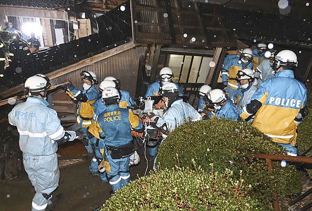<p>Police officers rescue a woman in her 90s from a collapsed house in Suzu, Ishikawa prefecture, Japan, on Saturday</p>