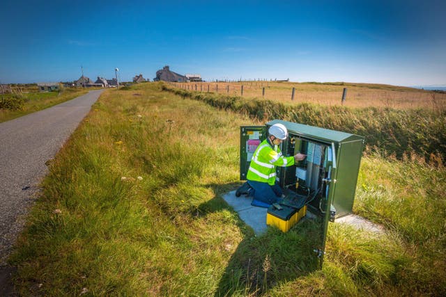 An engineer working on a traditional green street cabinet for broadband (BT/PA)