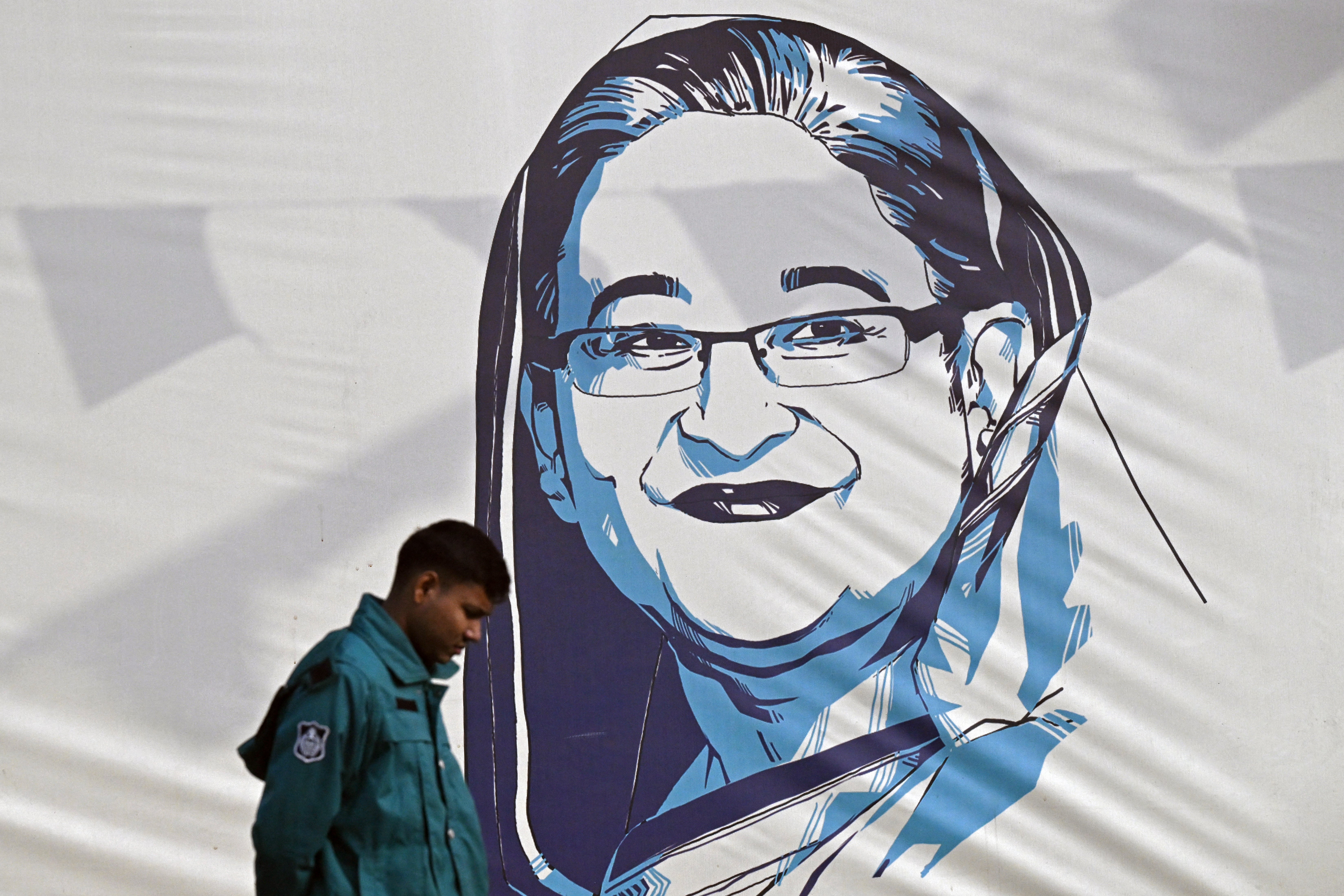 A policeman walks past a portrait of Bangladesh's Prime Minister Sheikh Hasina, in Dhaka