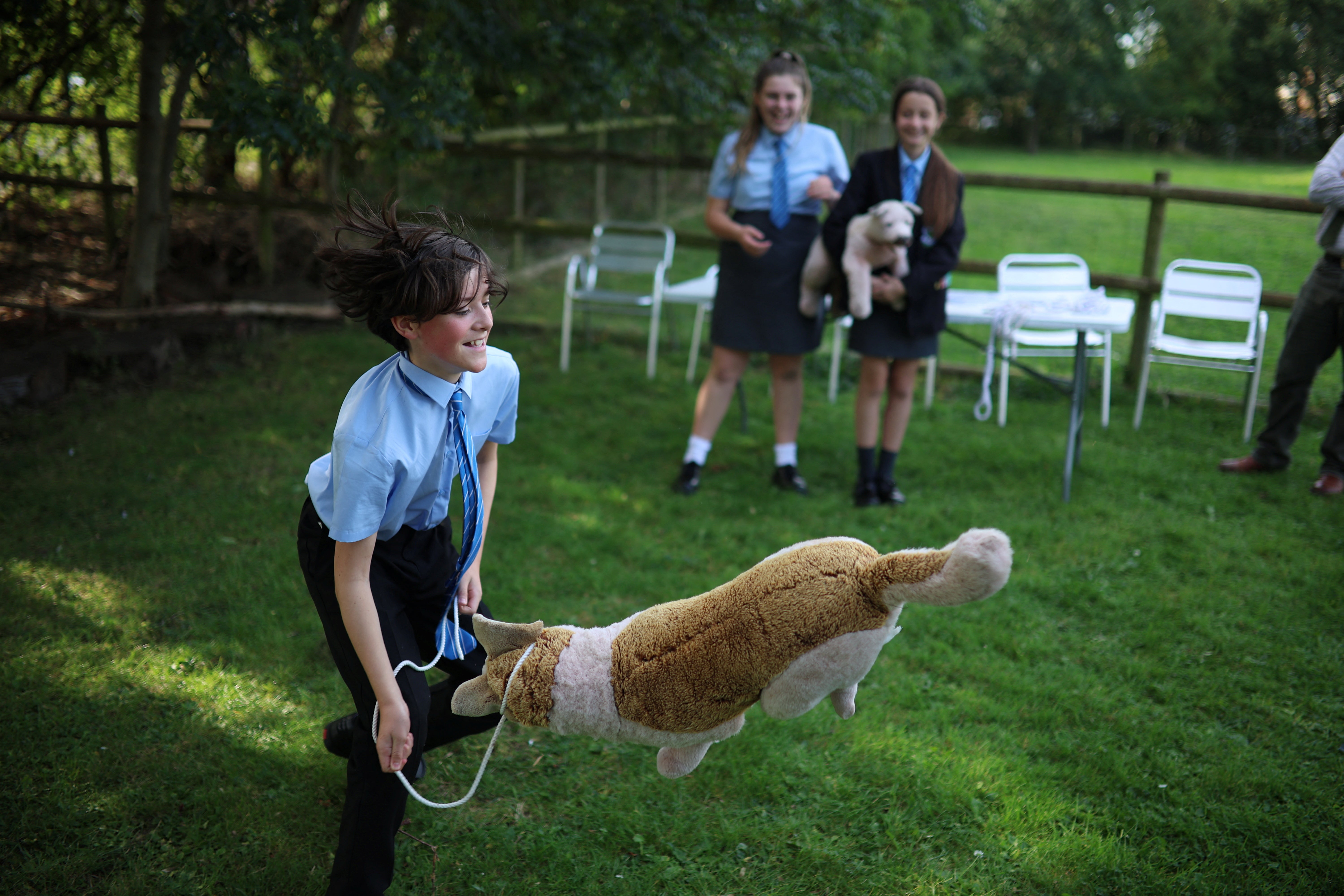 Corey jokes around while Megan and Abbie Swann watch as the students practise their head-collaring technique on toy dogs on the farm at Woodchurch High School