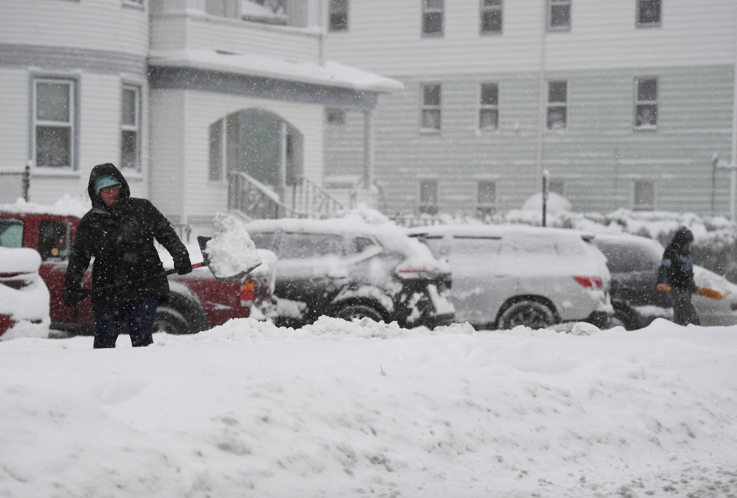 A woman throws snow while shovelling her car during the first winter storm of 2024 which is expected to bring heavy snowfall across the northeast United States