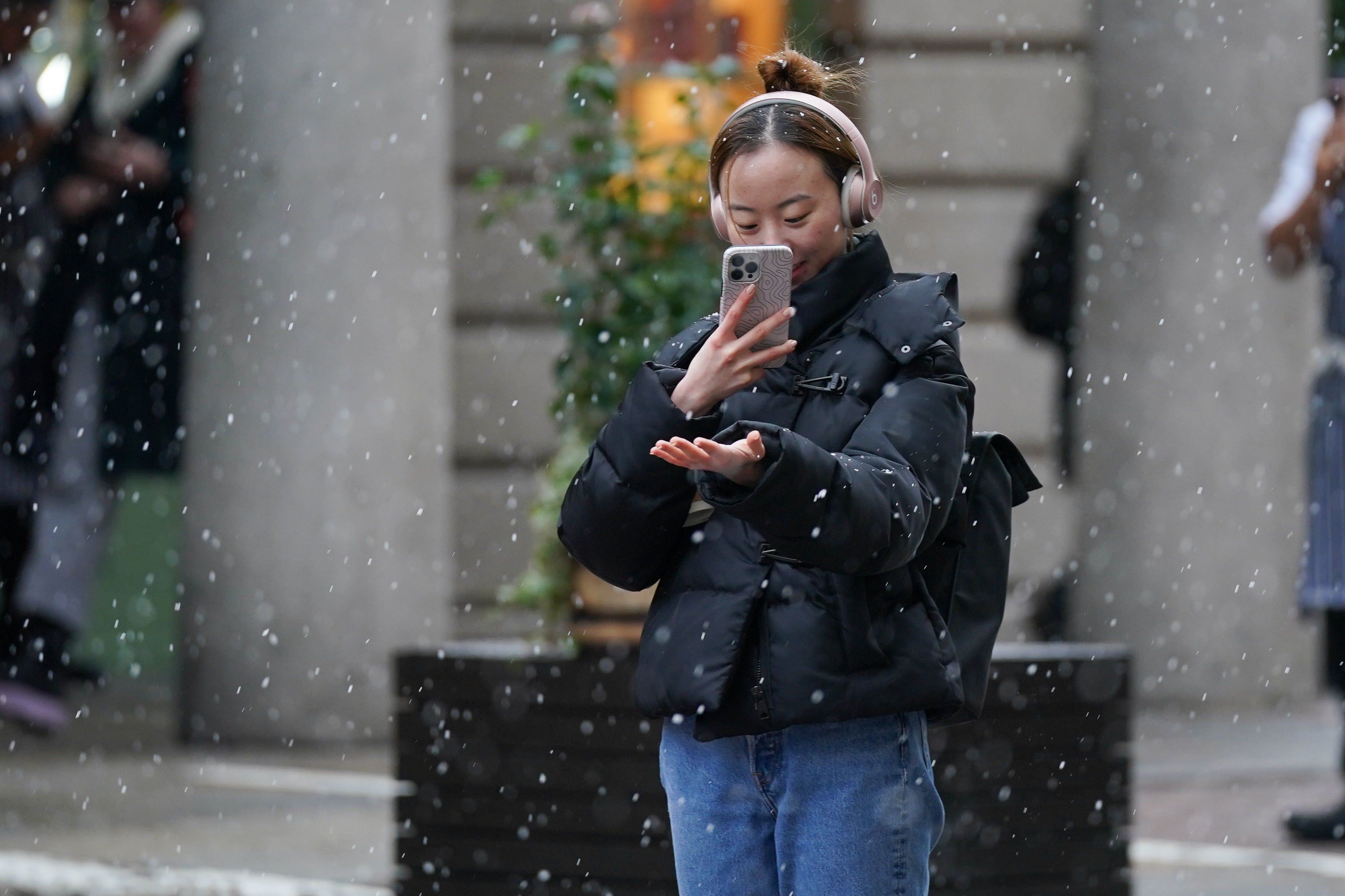 A person on her mobile phone capturing images of the snow in Covent Garden in London