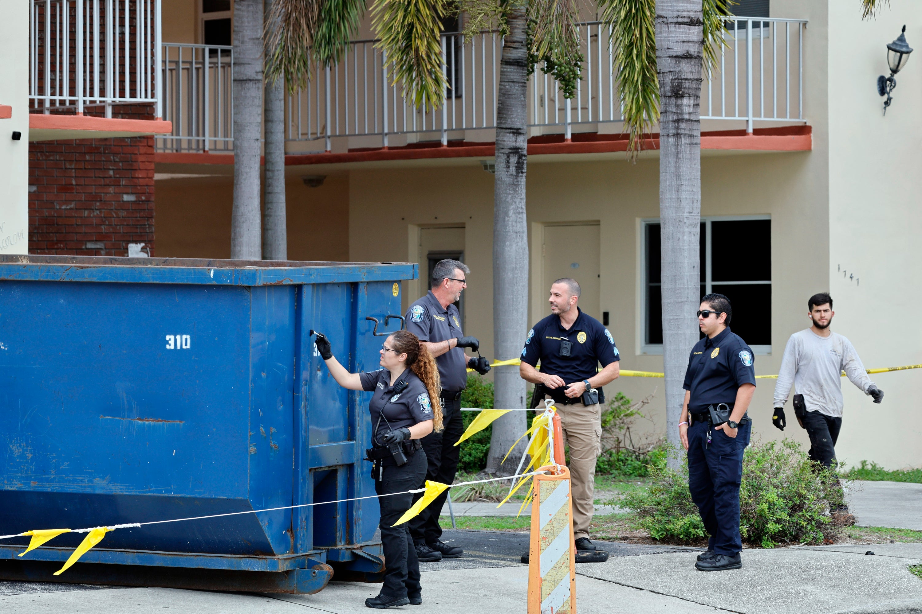 A crime scene investigator dusts for fingerprints at a large trash bin outside of an apartment complex in Hollywood, Florida, where construction workers found a dead baby on 8 January