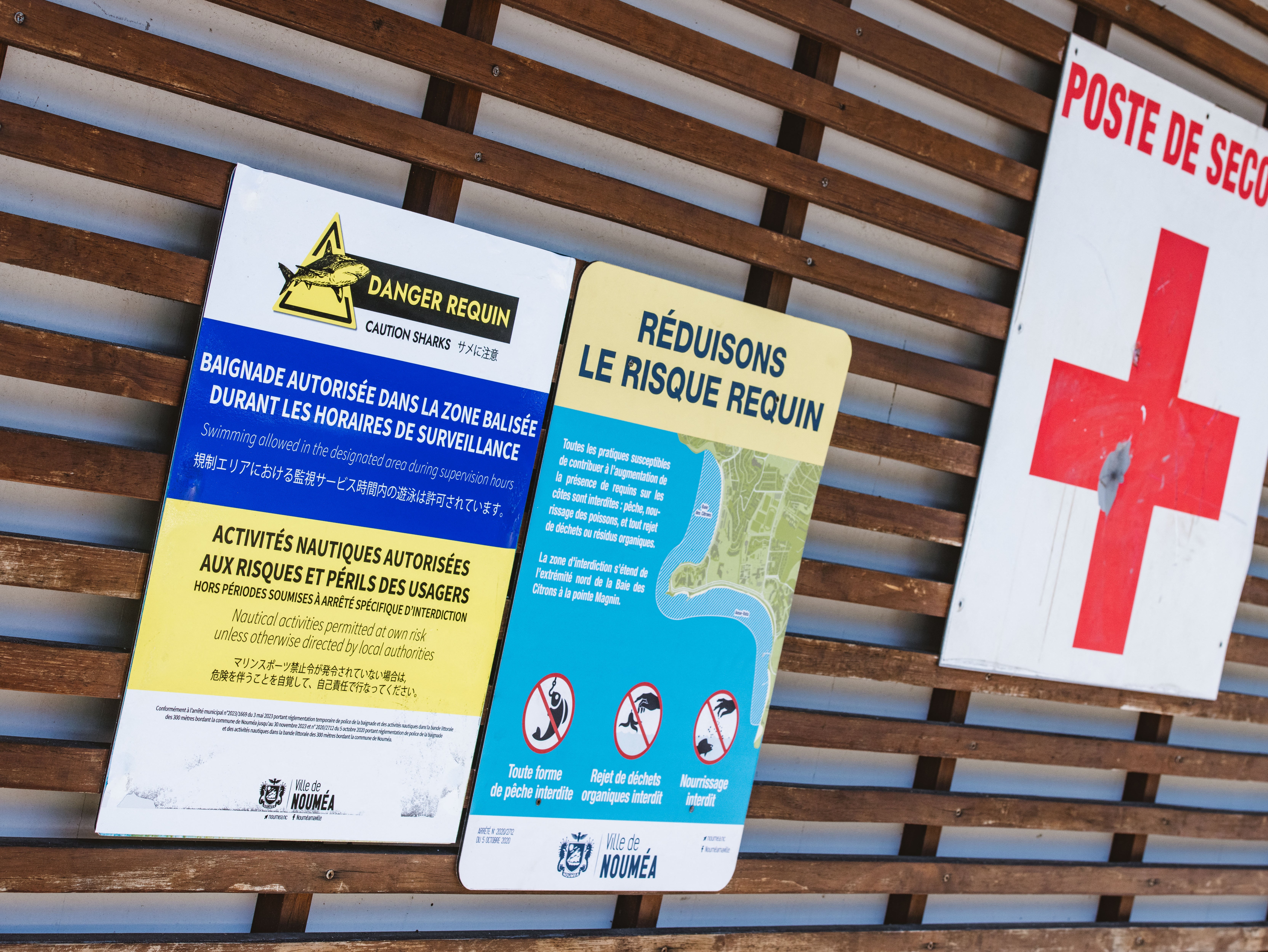 Signage at a lifeguard station warns of risk of shark attacks and indicates the presence of a perimeter of supervised swimming area protected by a newly-installed maritime net barrier at a beach along the Baie des Citrons bay in Noumea, New Caledonia, 6 December 2023