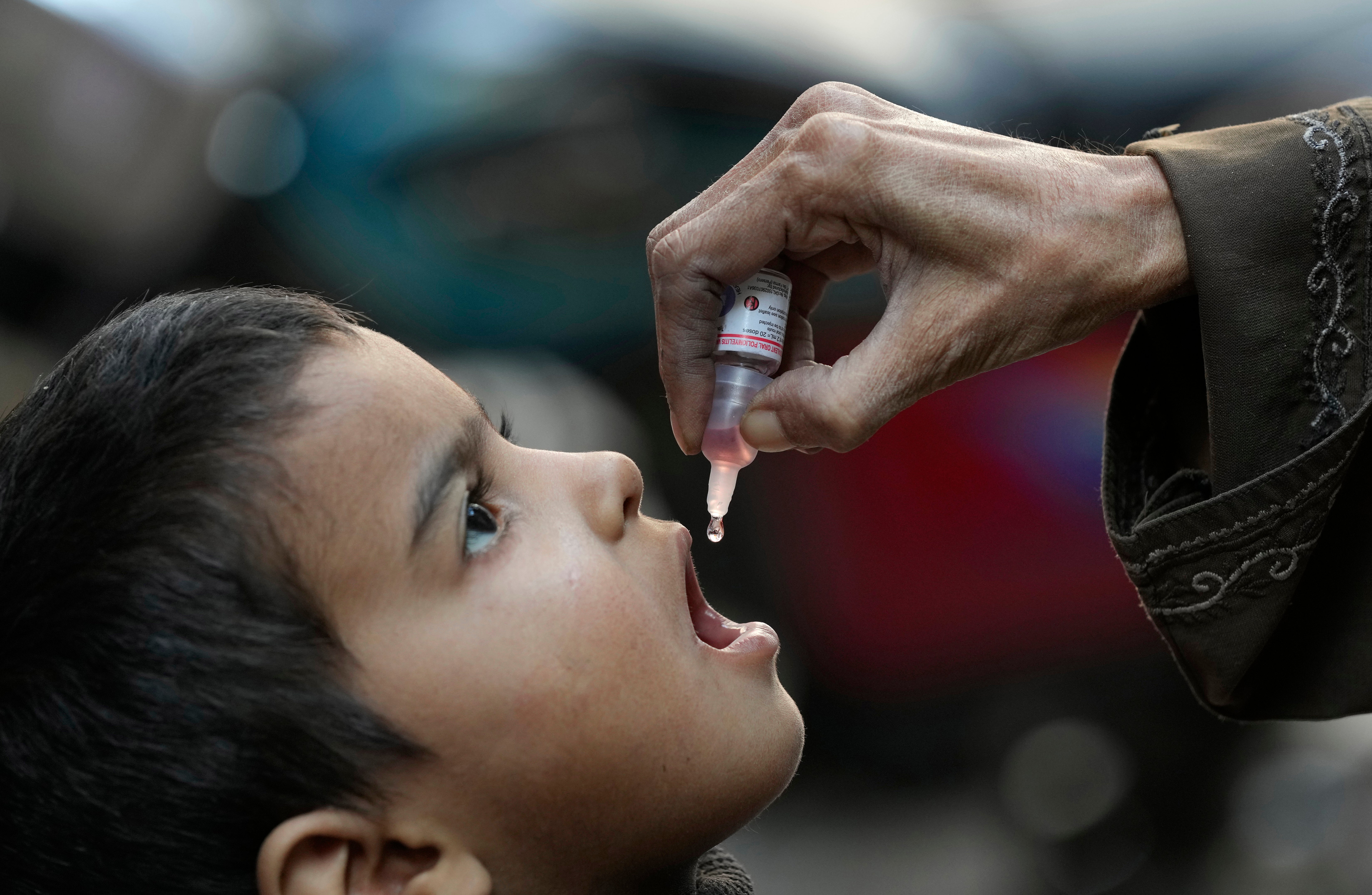 A health worker administers a polio vaccine to a child at a neighbourhood of Karachi, Pakistan