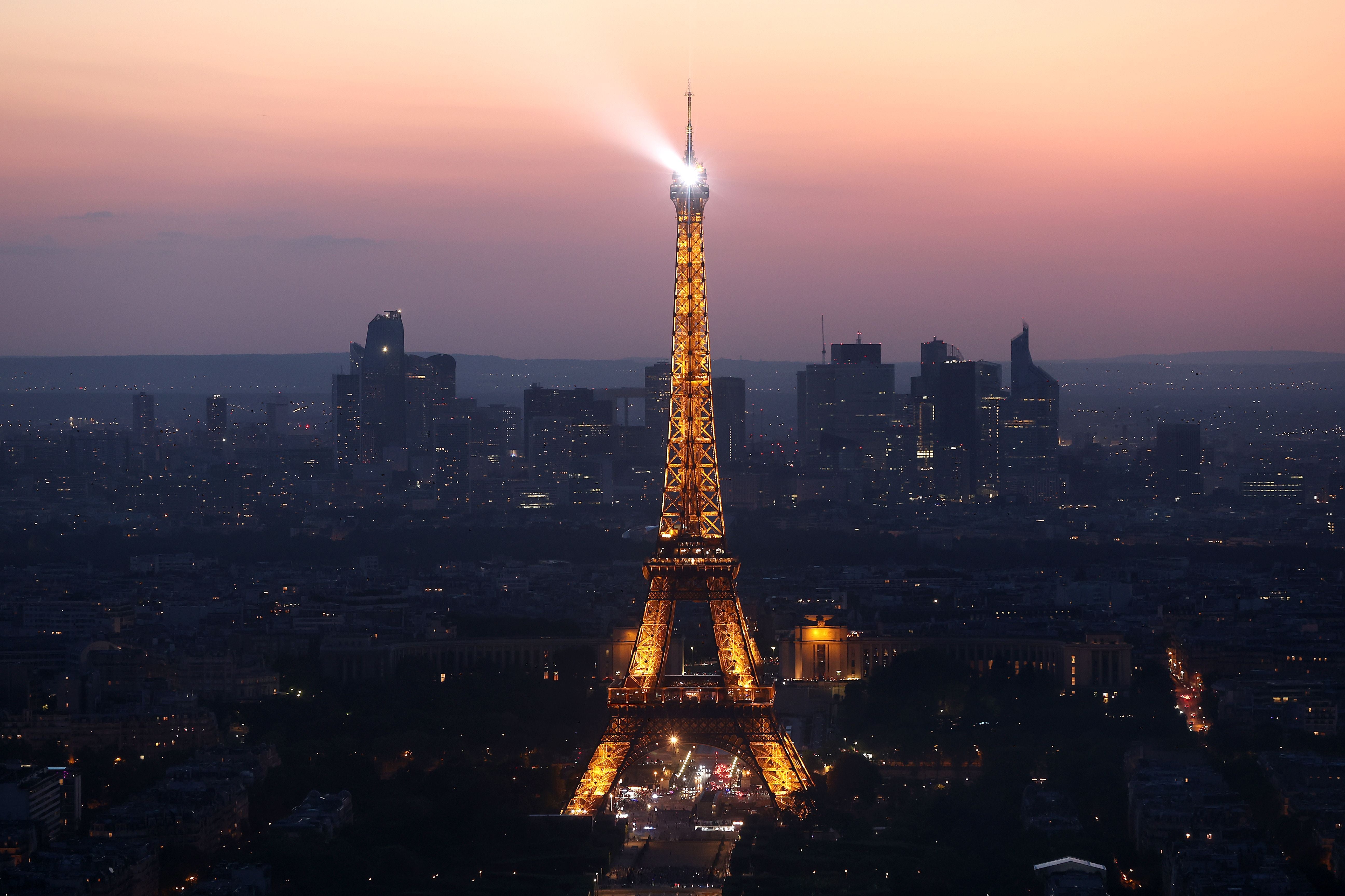 The Eiffel Tower stands illuminated after sunset in Paris