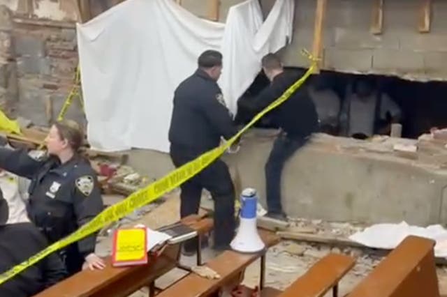 <p>An NYPD officer climbs into an alcove carved into the walls of the Chabad Lubavitch headquarters building in Brooklyn, New York</p>