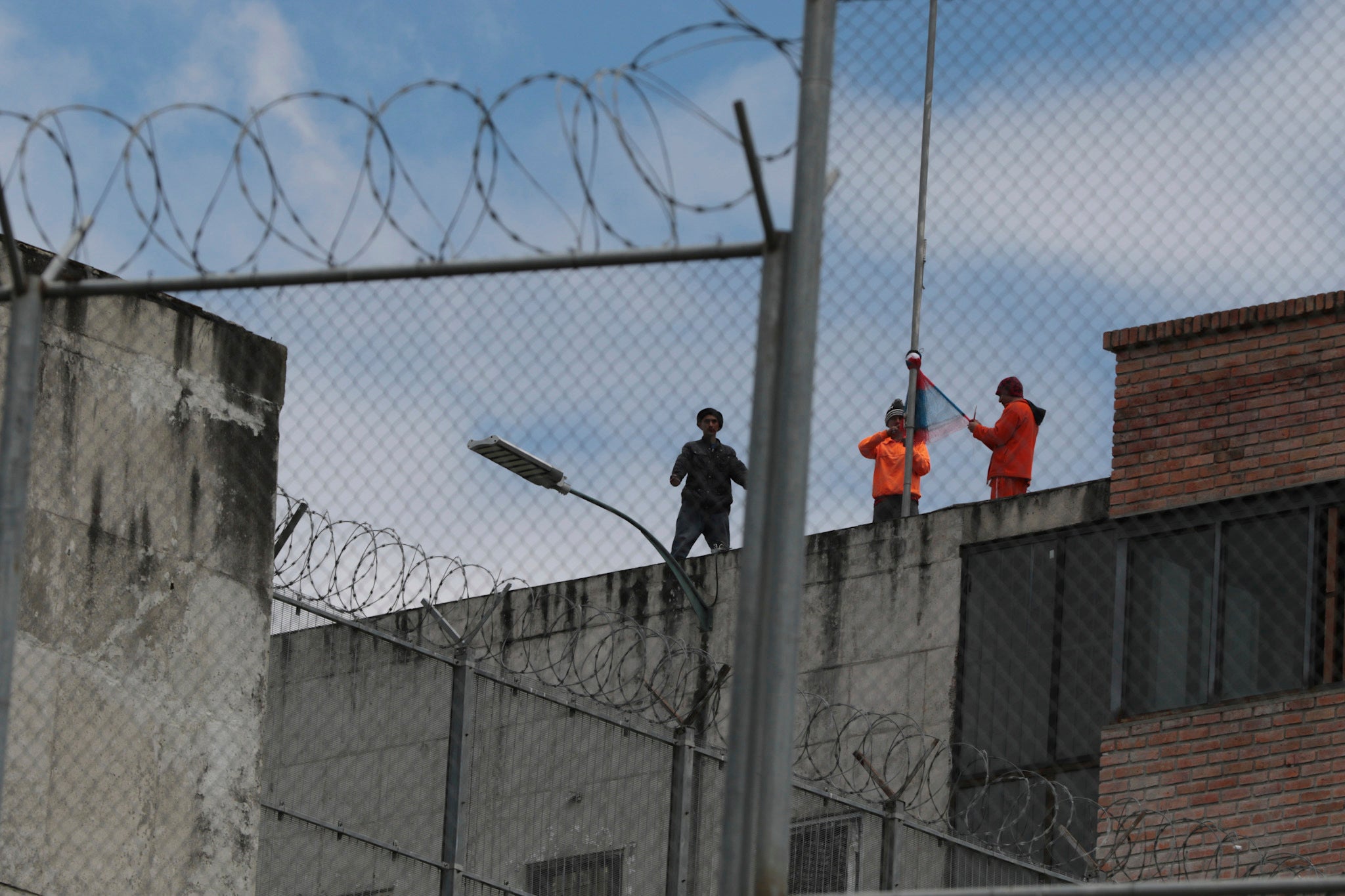 Inmates stand on the top of Turi jail during a prisoner riot in Cuenca