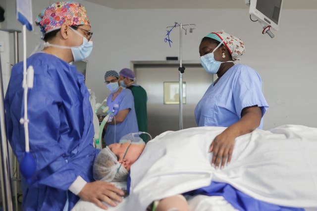<p>French doctor Aicha N’Doye, (R) a breast cancer surgeon who sings before her operations, sings to soothe a patient during anesthesia prior to surgery, in the operating room of the Bordeaux Nord polyclinic, in Bordeaux, south-western France, on December 11, 2023</p>
