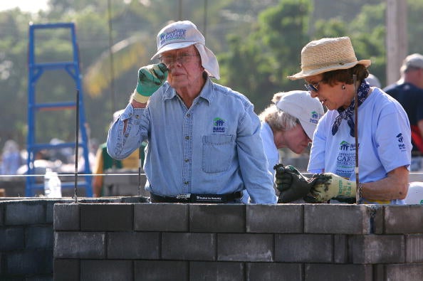 Carter adjusts his eyeglasses next to his wife Rosalynn as they help to build houses for the poor during the Habitat for Humanity project in Chiang Mai province on 16 November 2009