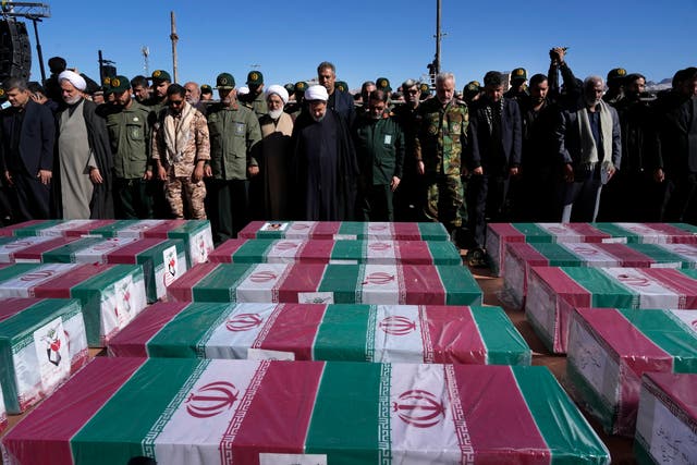 <p>People pray over the flag-draped coffins of victims of the bomb that exploded during a funeral service in the city of Kerman, Iran  </p>