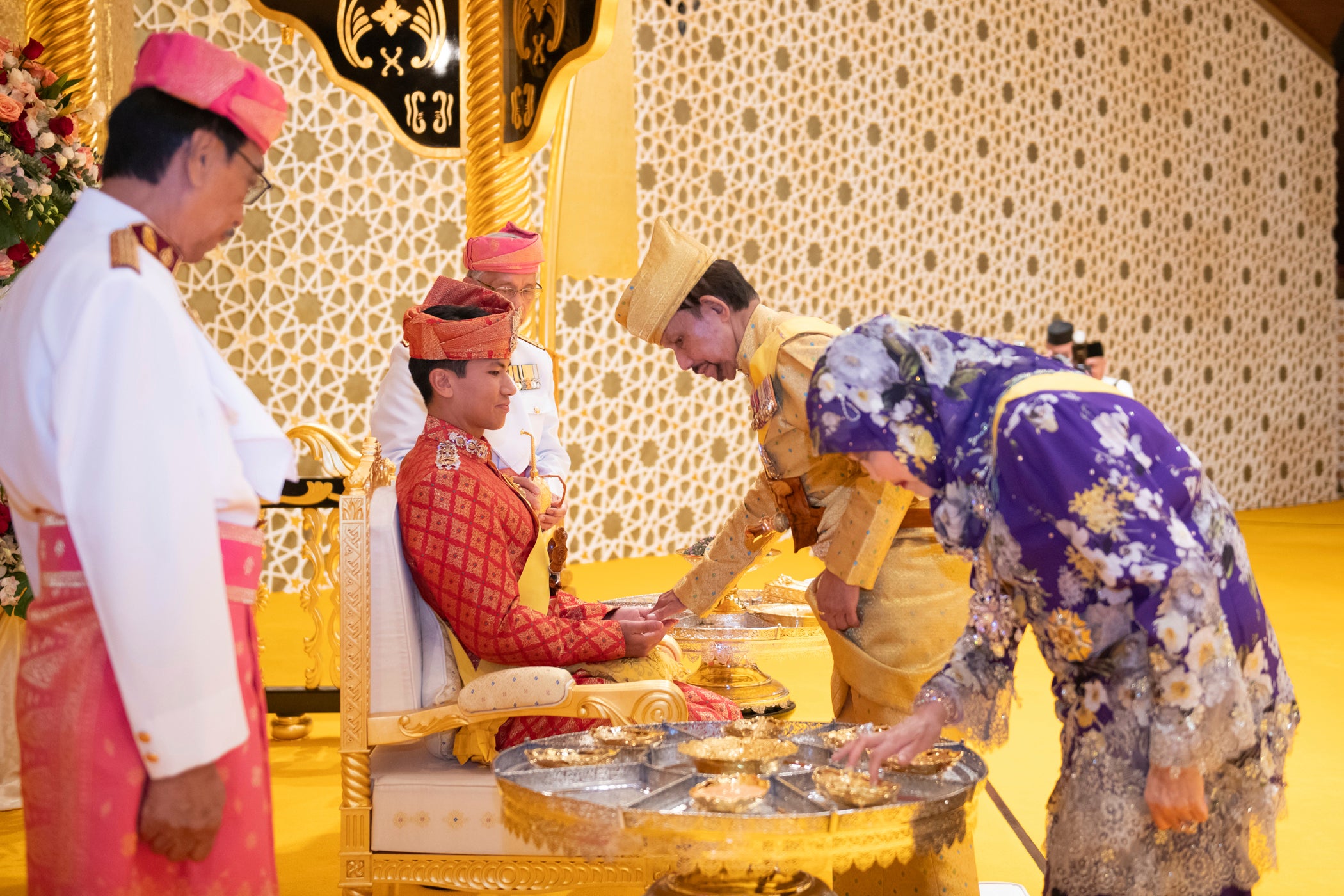 This picture taken by Brunei's Information Department on 10 January 2024 shows Brunei's Sultan Hassanal Bolkiah, centre right, greeting Brunei's Prince Abdul Mateen's, center, during the royal powdering ceremony at Istana Nurul Iman, ahead of his wedding to Anisha Rosnah, in Bandar Seri Begawan, Brunei