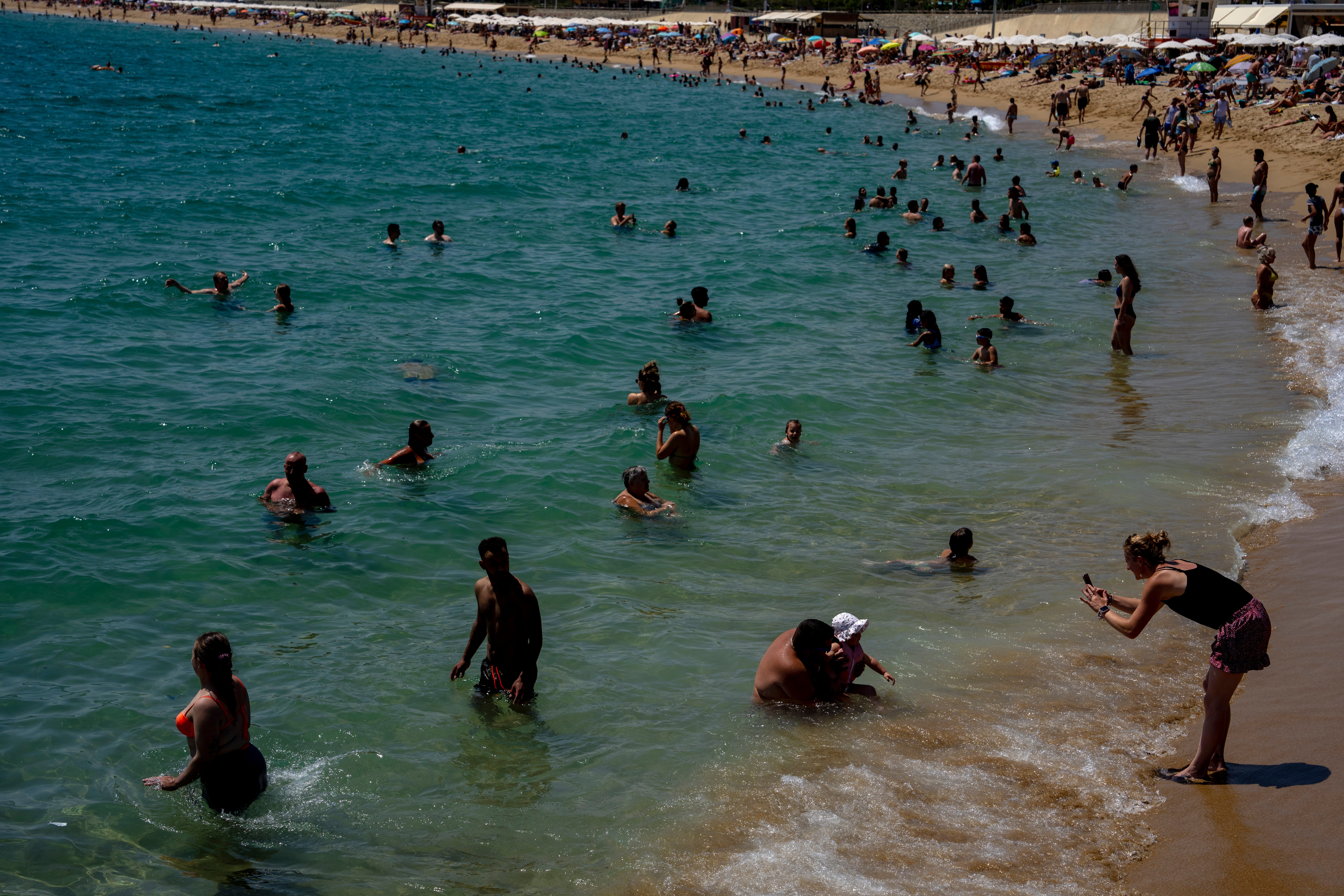 People cool off on a beach in Barcelona, Spain