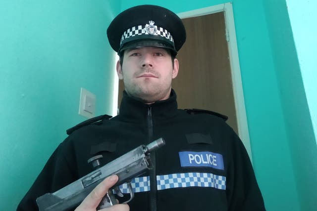 <p>Reed Wischhusen pictured holding a gun while wearing a fake police uniform</p>