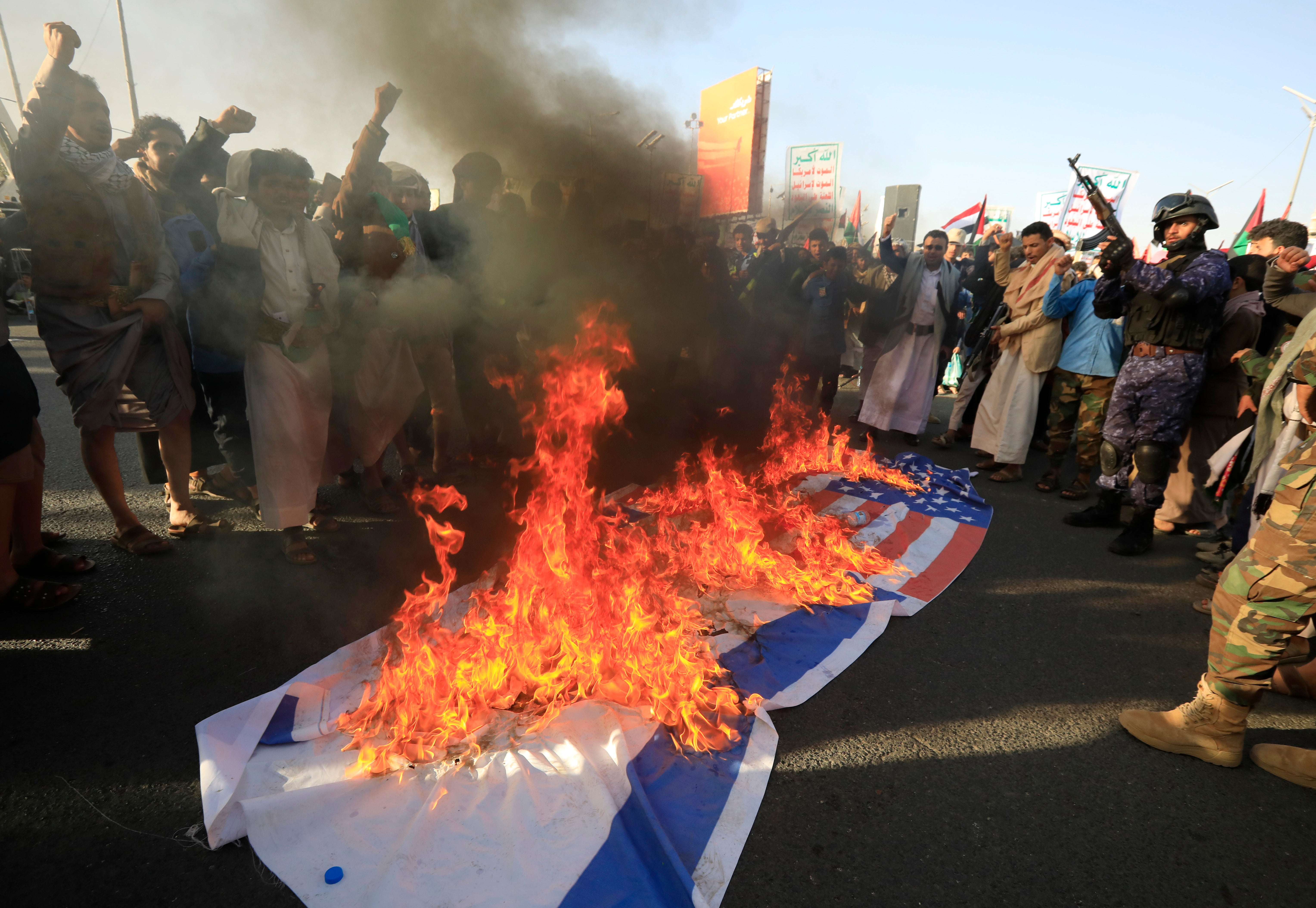 Protesters burn Israeli and US flags in Yemen yesterday after US and UK airstrikes on Houthi military sites