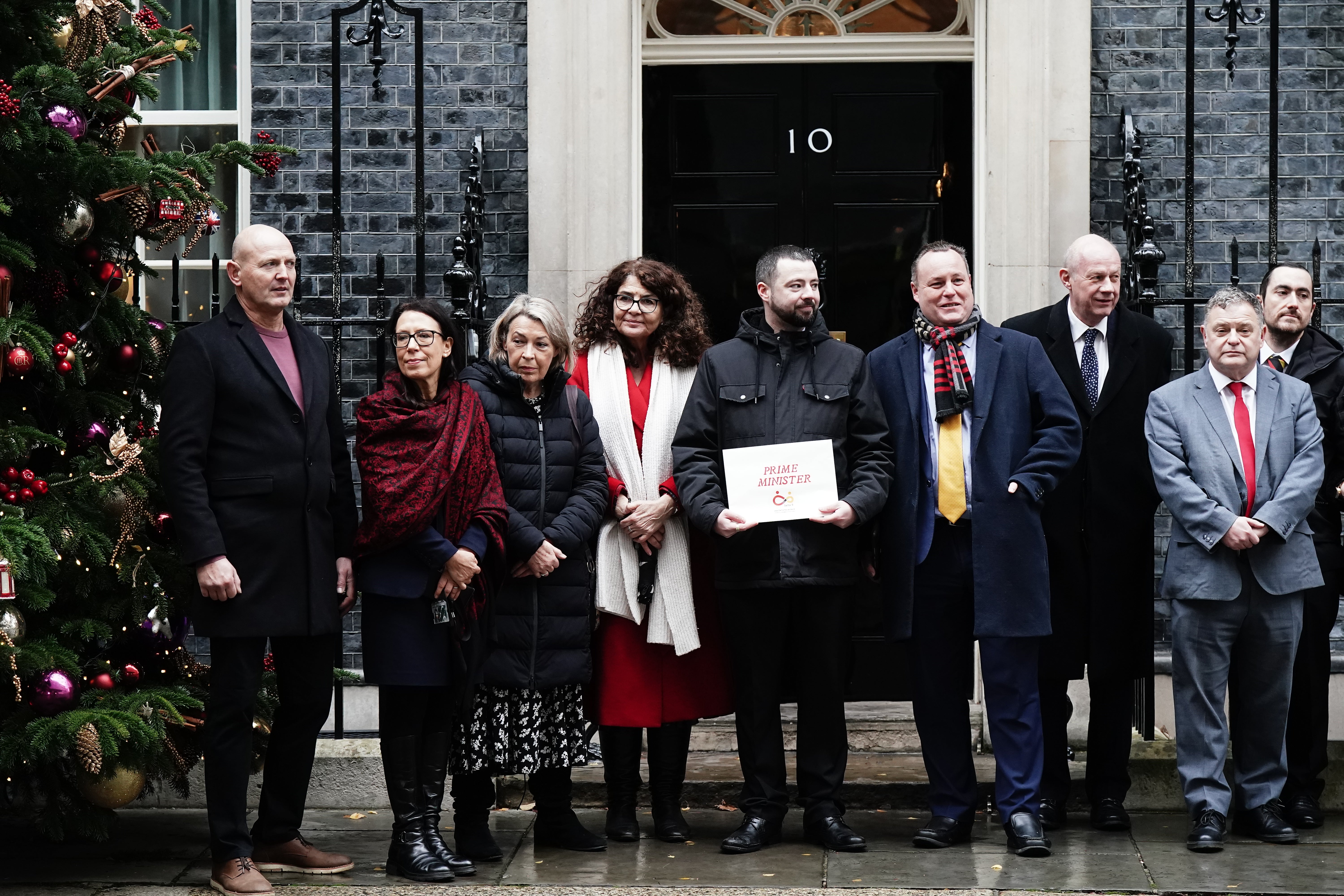 Dame Diana Johnson (fourth from left), Jason Evans (fifth from left), Damian Green (sixth from left) and other campaigners in Downing Street with a letter calling for faster compensation for victims of the infected blood scandal