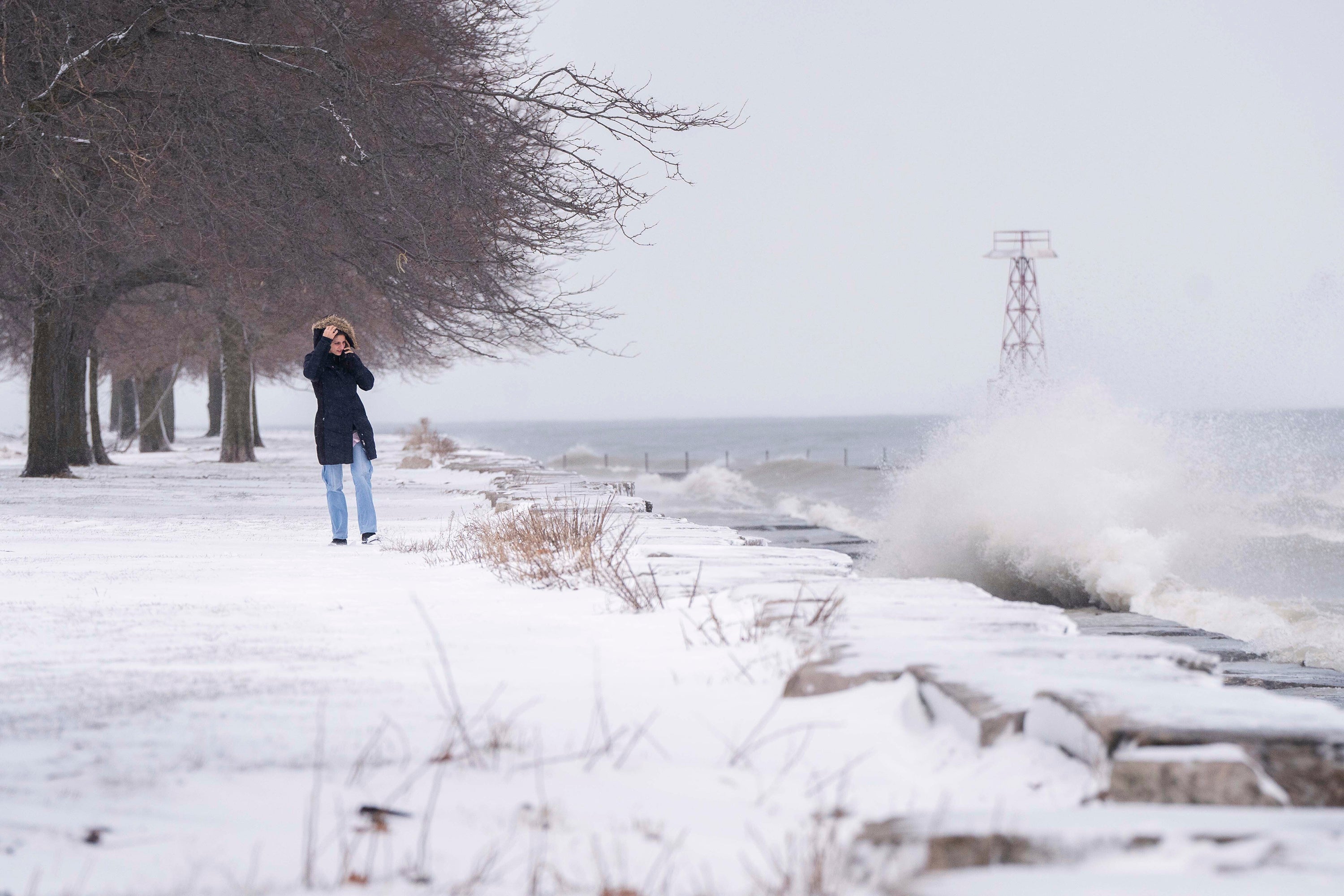 A person looks at Lake Michigan’s strong waves near Foster Beach after a major snowstorm hit the Chicago area