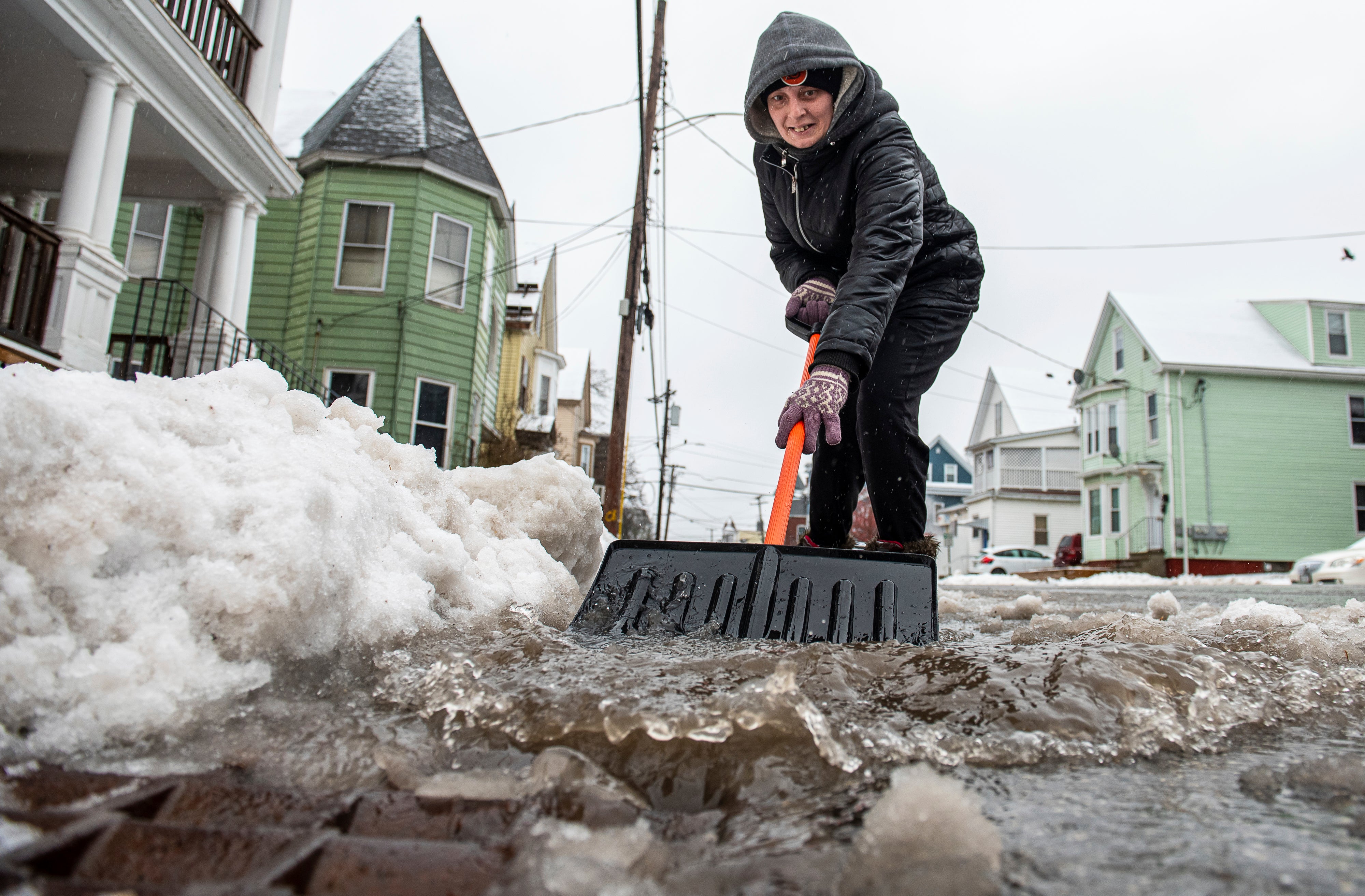 Amber Vallee pushes water down Walnut Street in Lewiston, Maine, Saturday morning, Jan 13, 2024