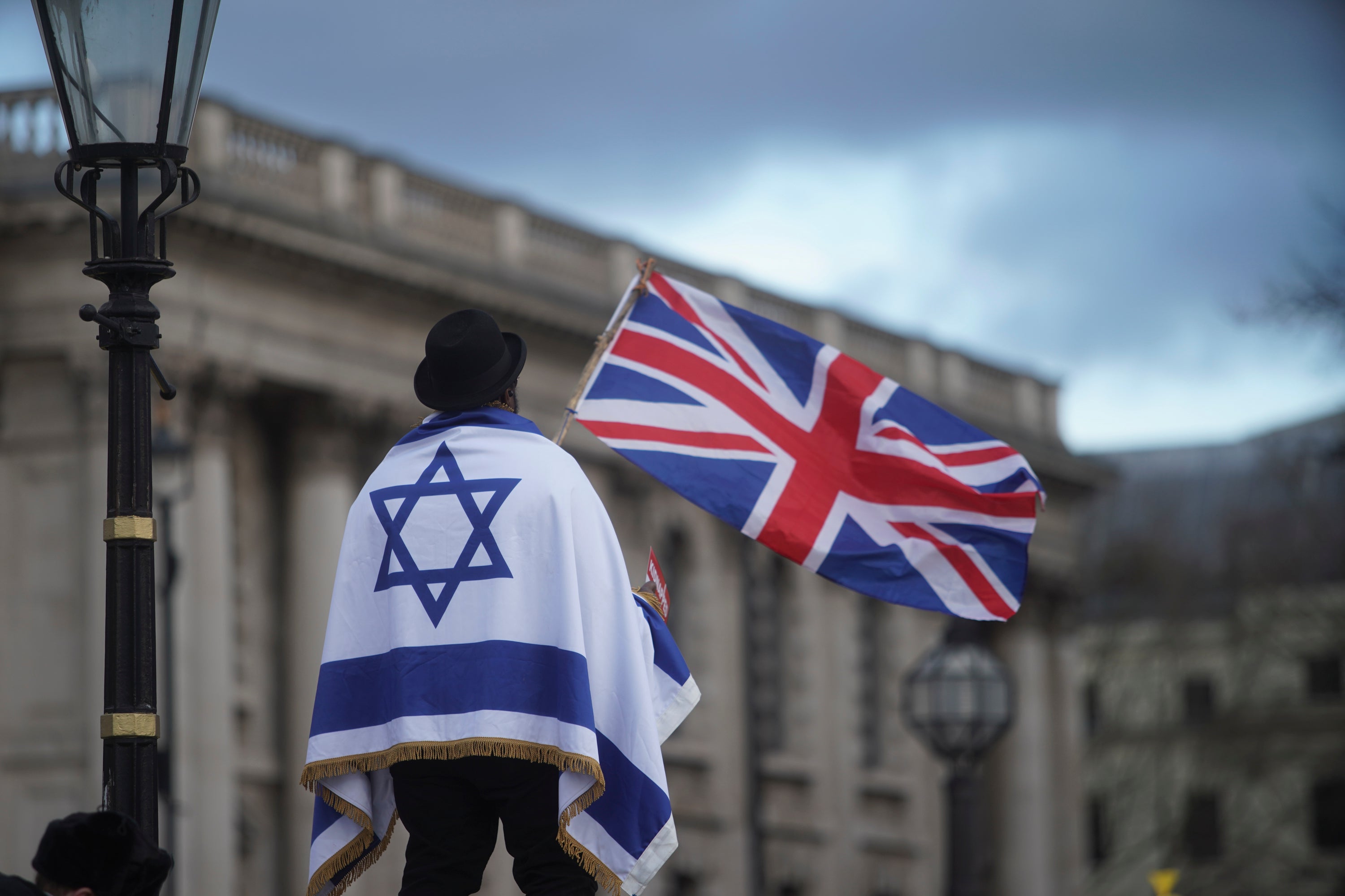 A man draped in the Israel flag flies the Union Jack