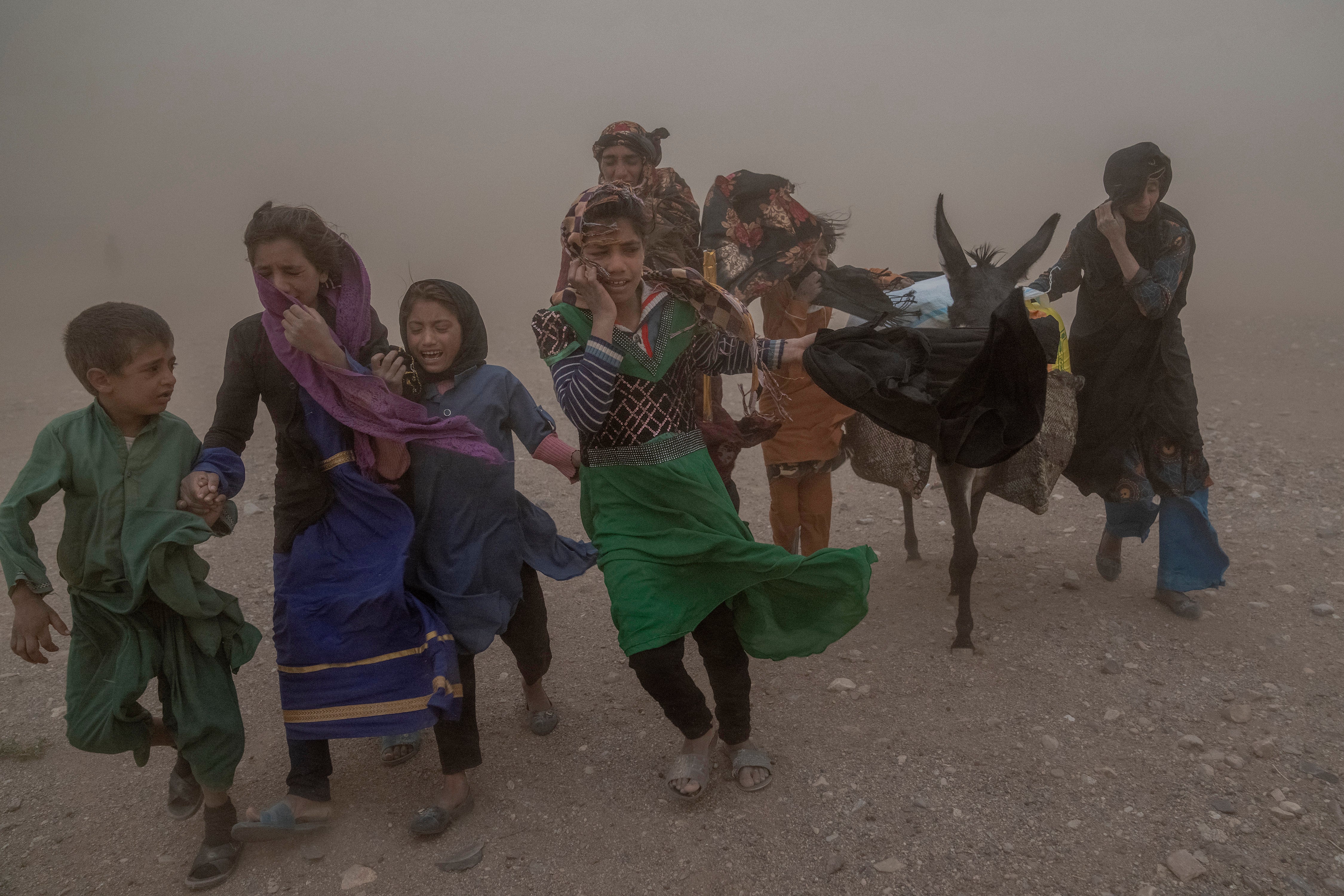 Afghan girls and women carry donated aid to their tents in Zinda Jan district of Herat