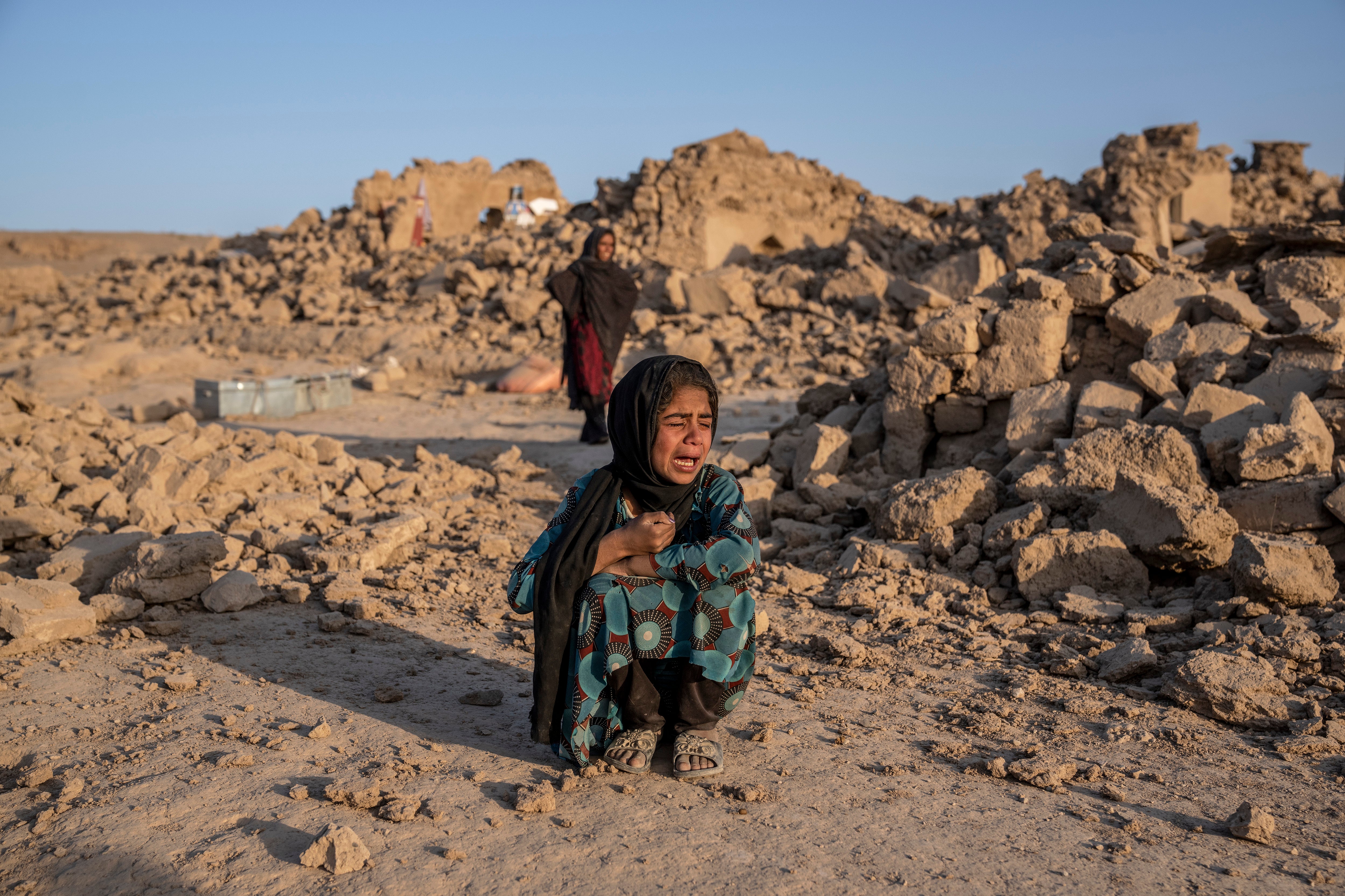 An Afghan girl cries in front of her house that was destroyed by the earthquake in Zinda Jan district in Herat