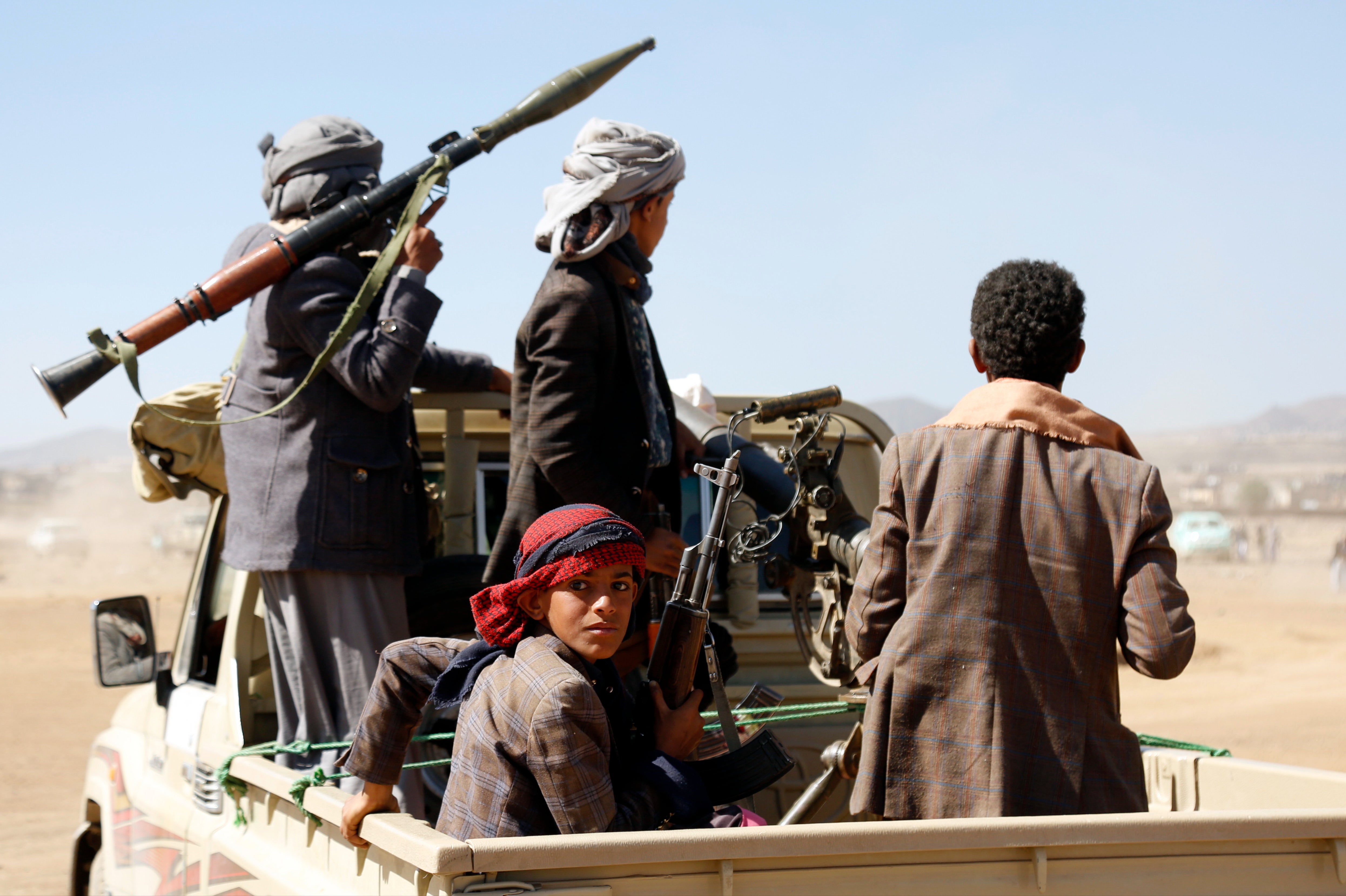 <p>Houthi militiamen parade weapons on from the back of a pick up truck </p>