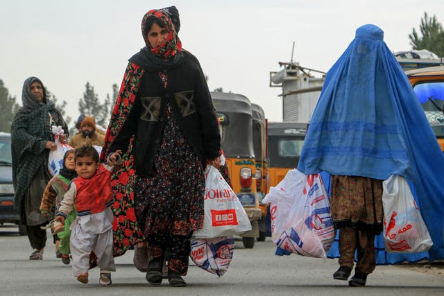 <p>Afghan women carry aid packages which includes food, clothes, and sanitary materials distributed by a local charity foundation in Herat</p>