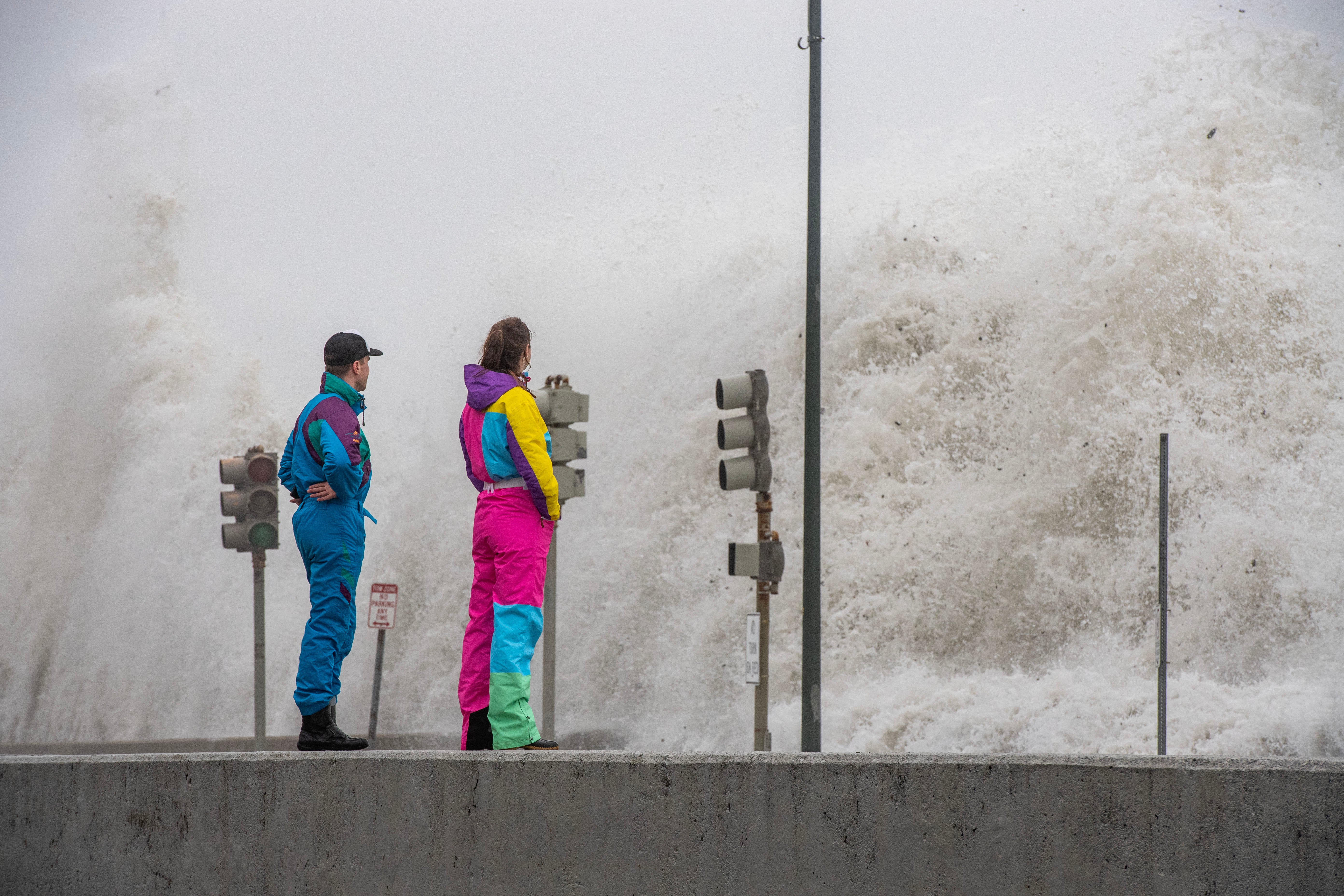 People watch waves crash over the sea wall in Revere, Massachusetts