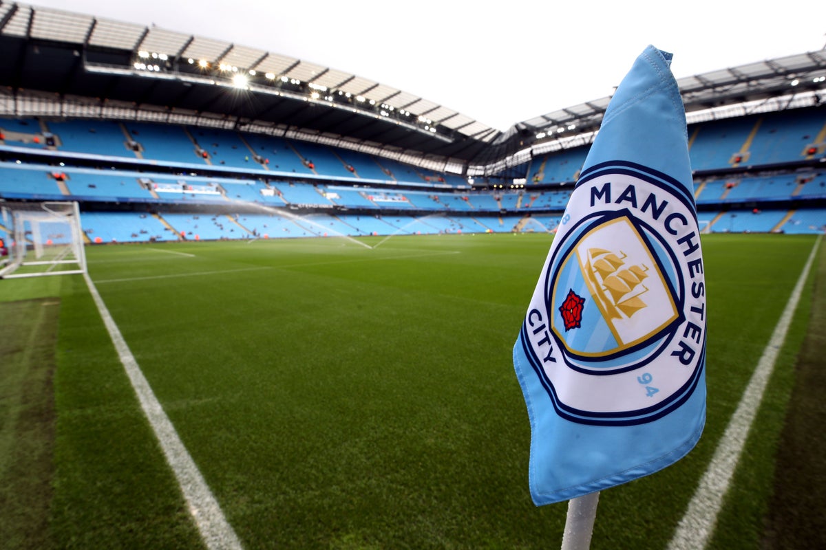 Wide view of the Etihad Stadium during a Premier League match involving Manchester City, with full stands and the pitch under floodlights.