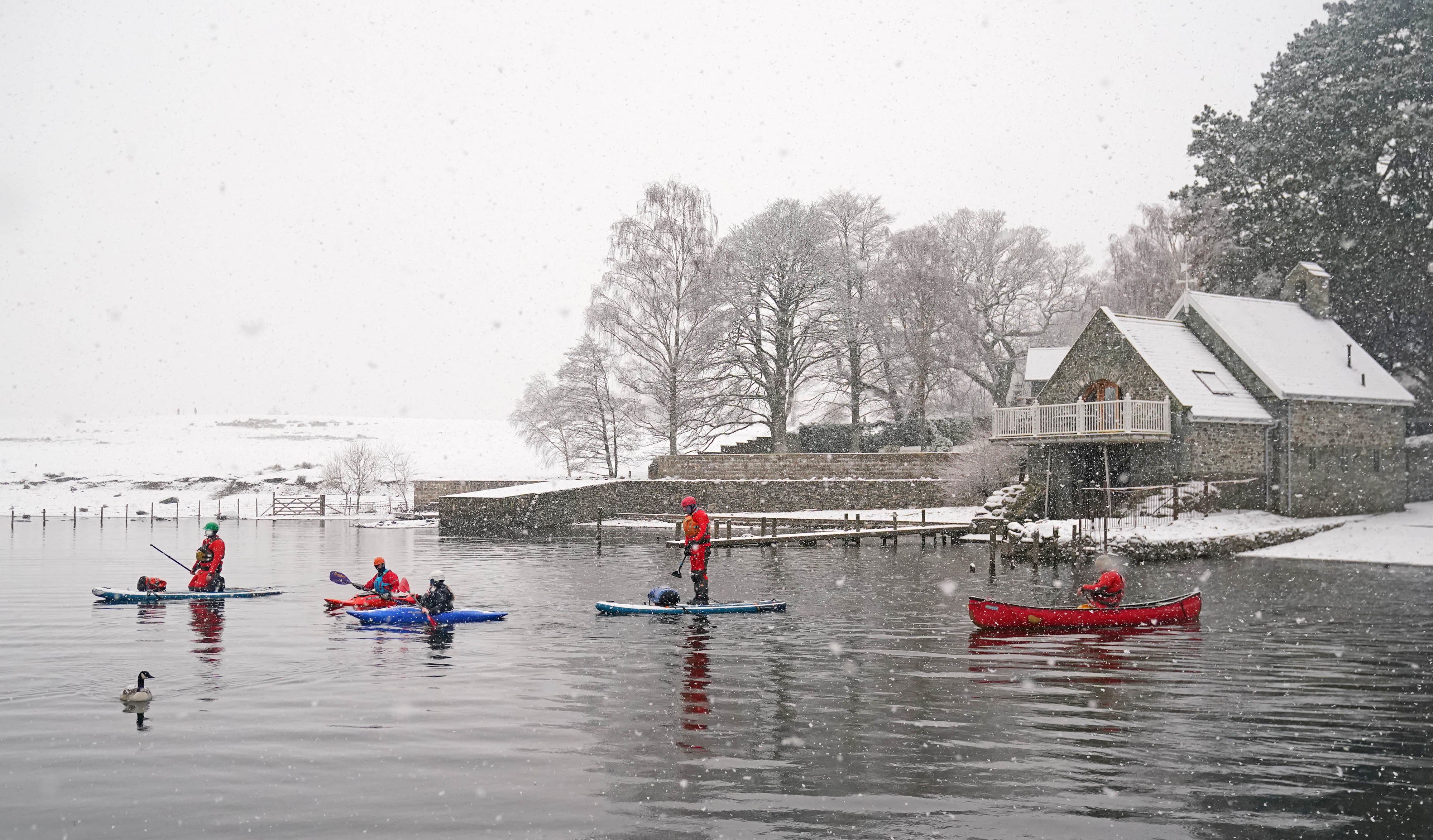Canoeists, kayakers and paddleboarders in snowy conditions on Derwent Water, Keswick in Cumbria