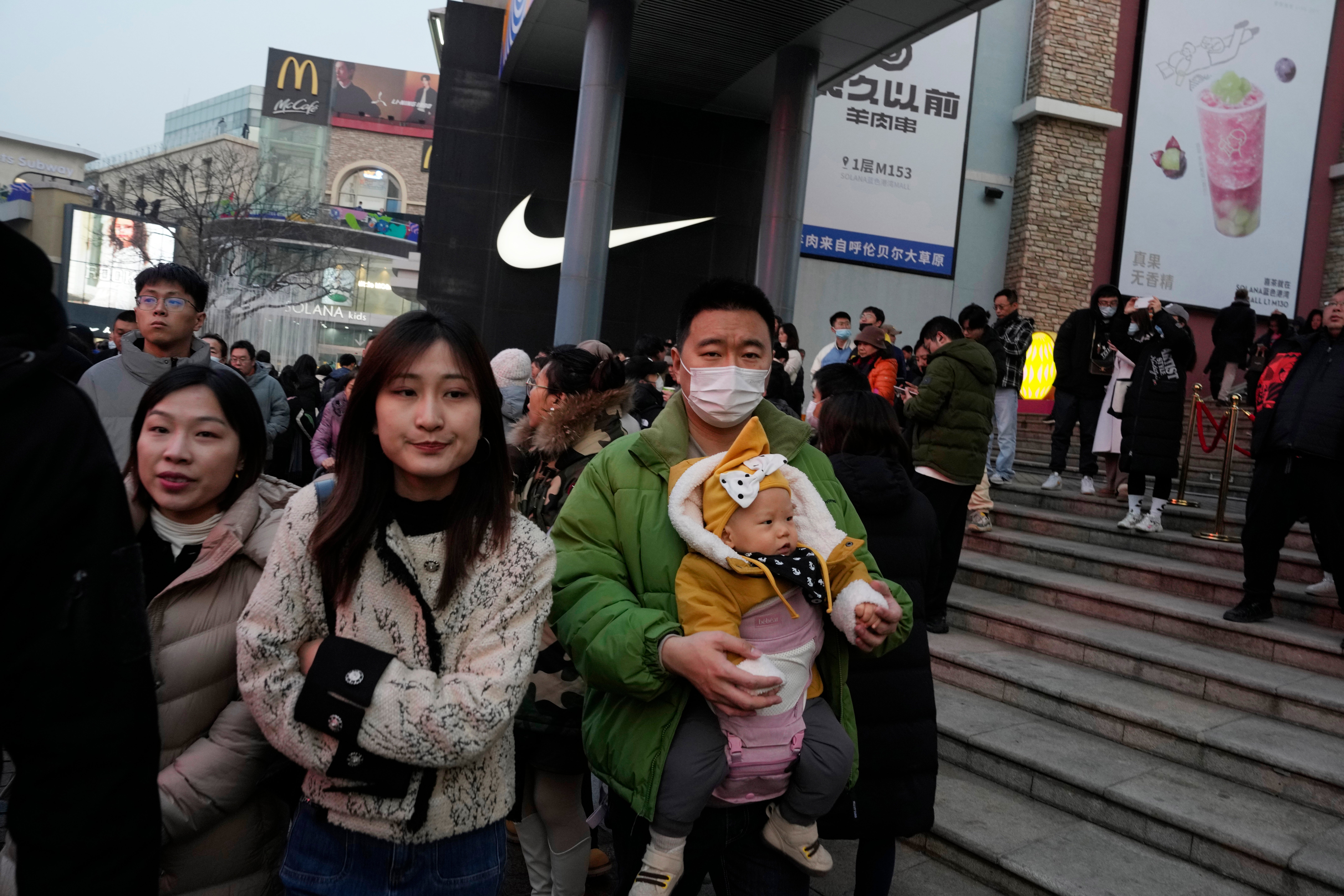 A man is pictured holding a baby at a Beijing shopping mall – but there are too few Chinese being born