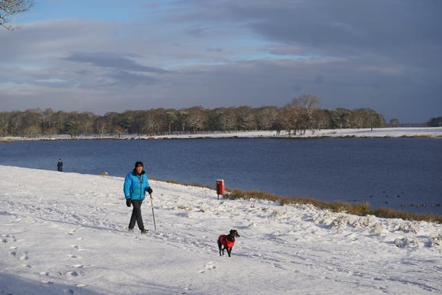 A dog walker in the snow in Tatton Park, Knutsford, Cheshire (Martin Rickett/PA)