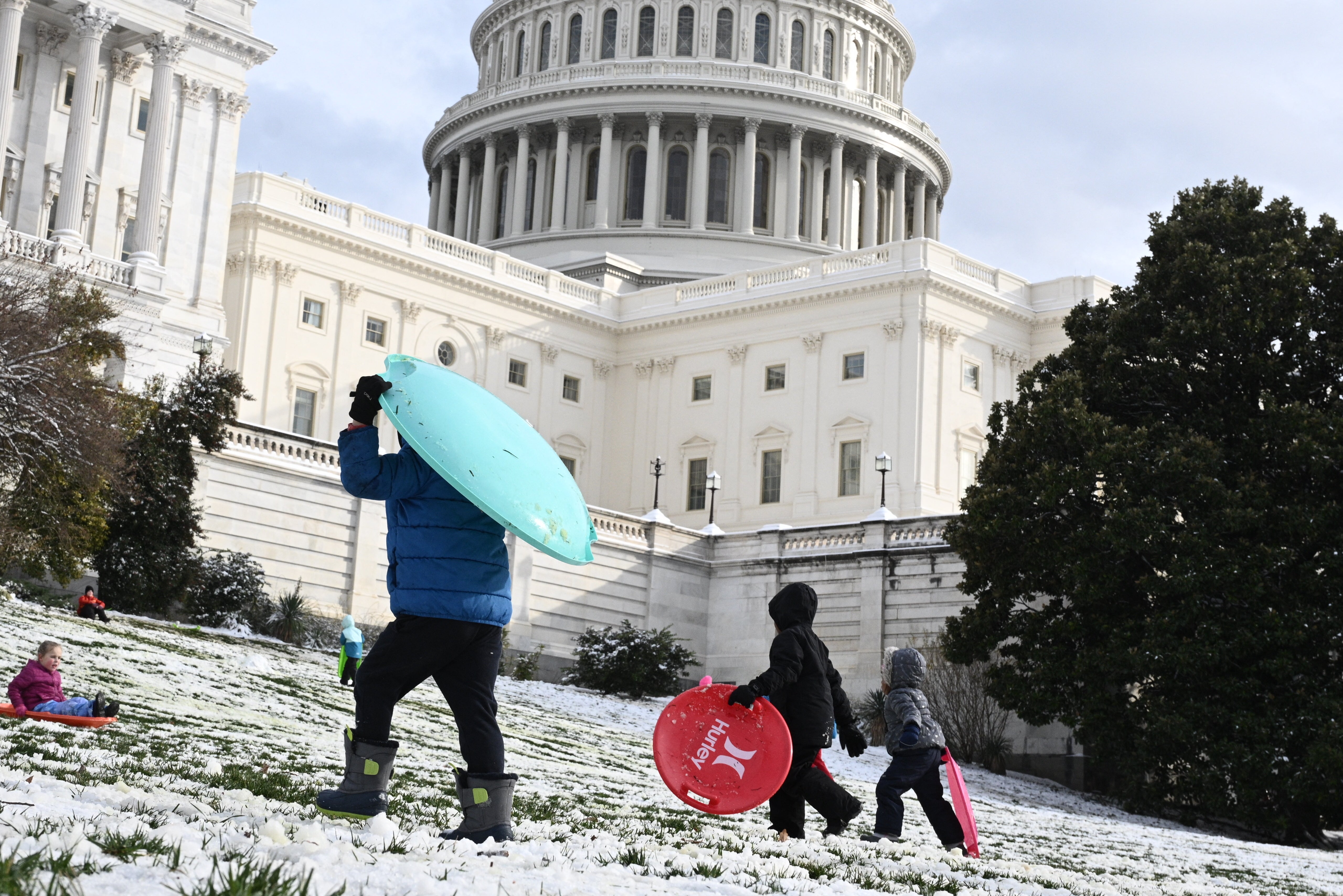 People carry sleds up a hill by the US Capitol in Washington, DC