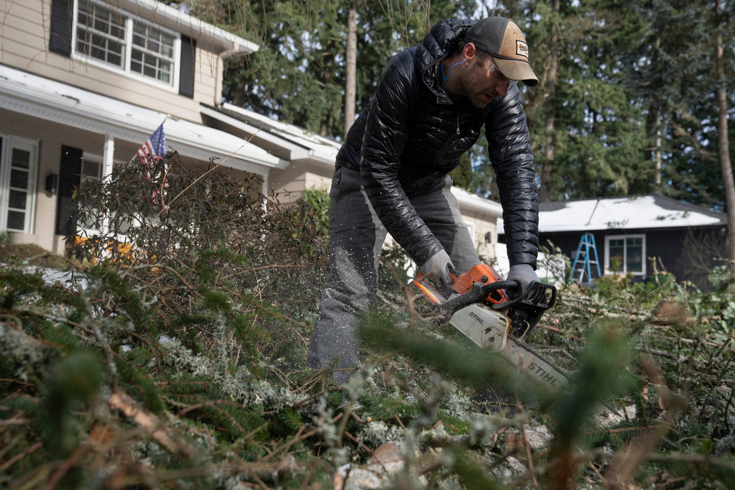 A man clears trees that fell in his front yard following a winter storm in Lake Oswego, Oregon on 16 January 2024