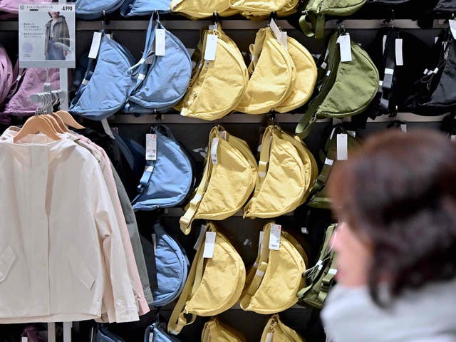 <p>A woman walks past a display of bags at a Uniqlo retail store in Tokyo on 16 January 2024. </p>