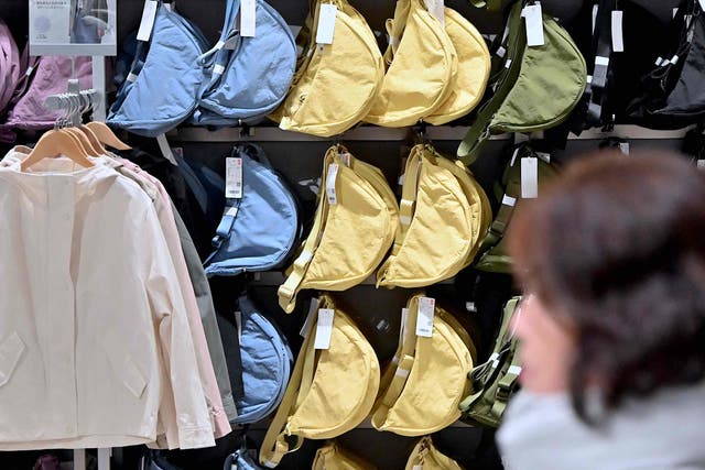 <p>A woman walks past a display of bags at a Uniqlo retail store in Tokyo on 16 January 2024. </p>