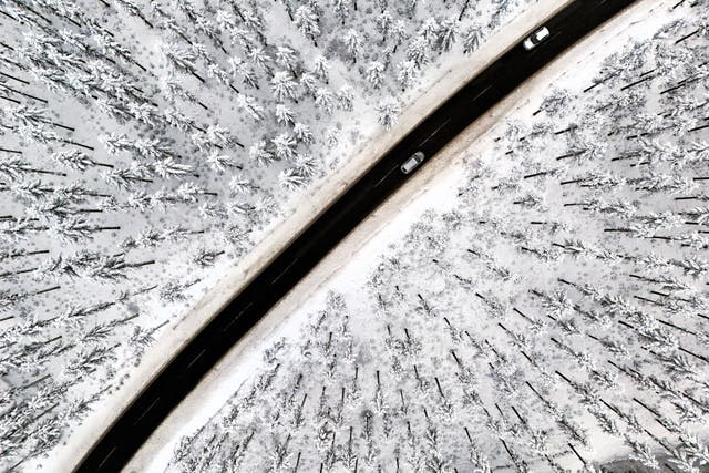 <p>An aerial view shows cars on a road crossing the snow-covered landscape at the Kahler Asten mountain near Winterberg, western Germany on 1 December, 2023</p>
