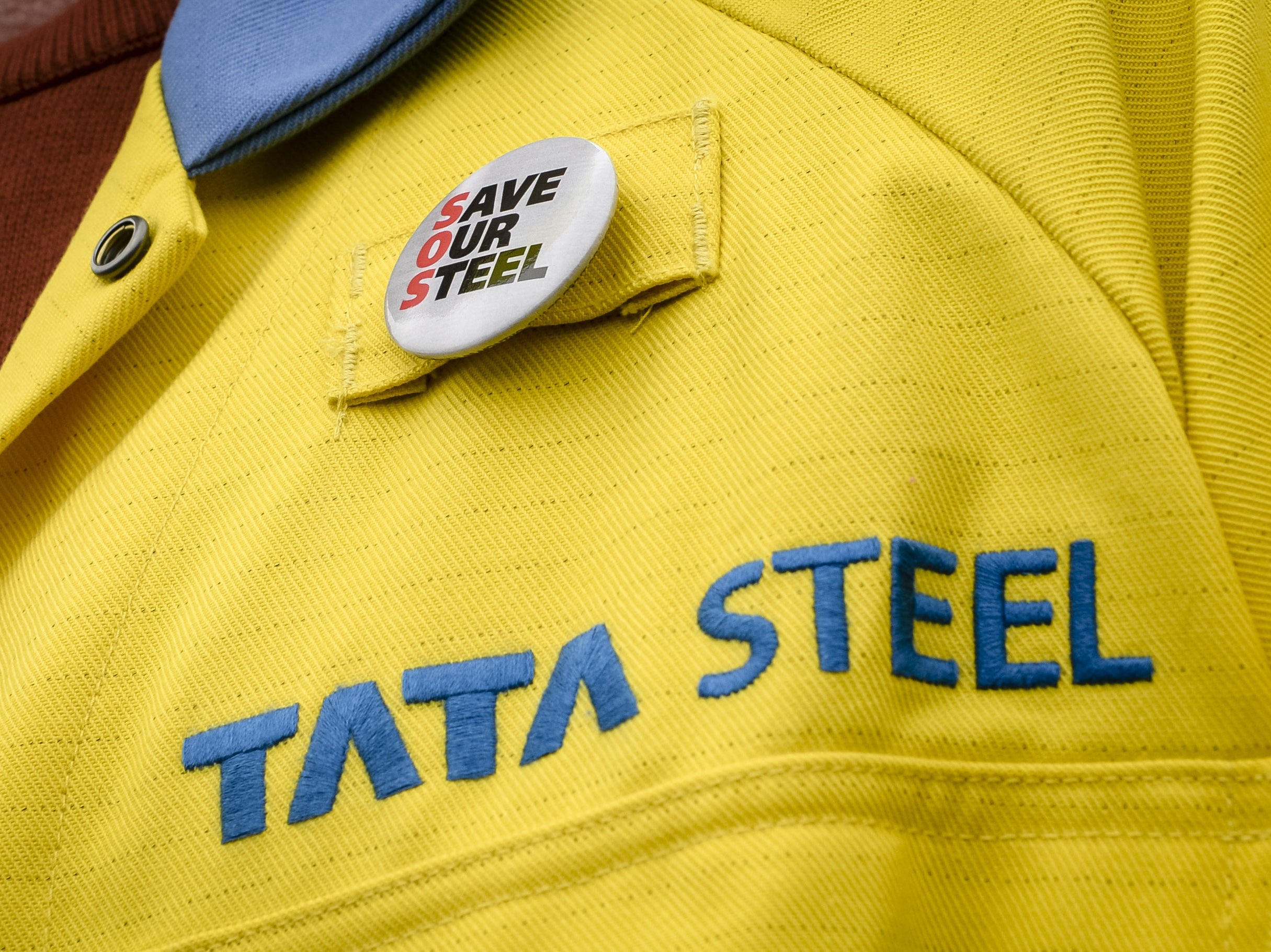 A steelworker wears a badge on his jacket outside the UK’s largest steelworks in Port Talbot
