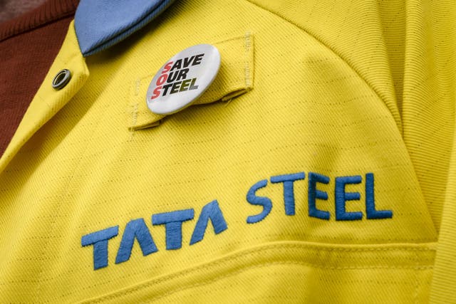 A steel worker wearing a badge on his jacket outside the UK’s largest steel works in Port Talbot (PA)