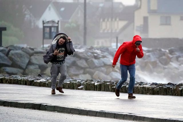 <p>People walking in high winds at Salthill, Galway, during Storm Isha</p>