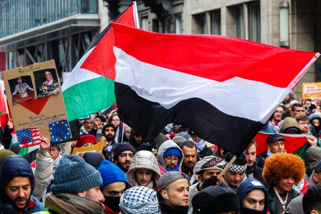 <p>People hold a placard of the Houthi movement leadership and a flag of Yemen during a pro-Palestinian demonstration in Brussels, Belgium, 21 January 2024</p>