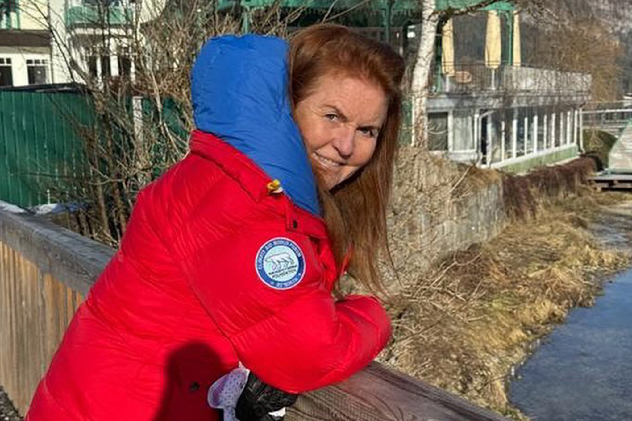 Sarah Ferguson shared a photo of herself smiling and dressed a vivid red warm winter coat while leaning on a small bridge over a river, apparently in Austria