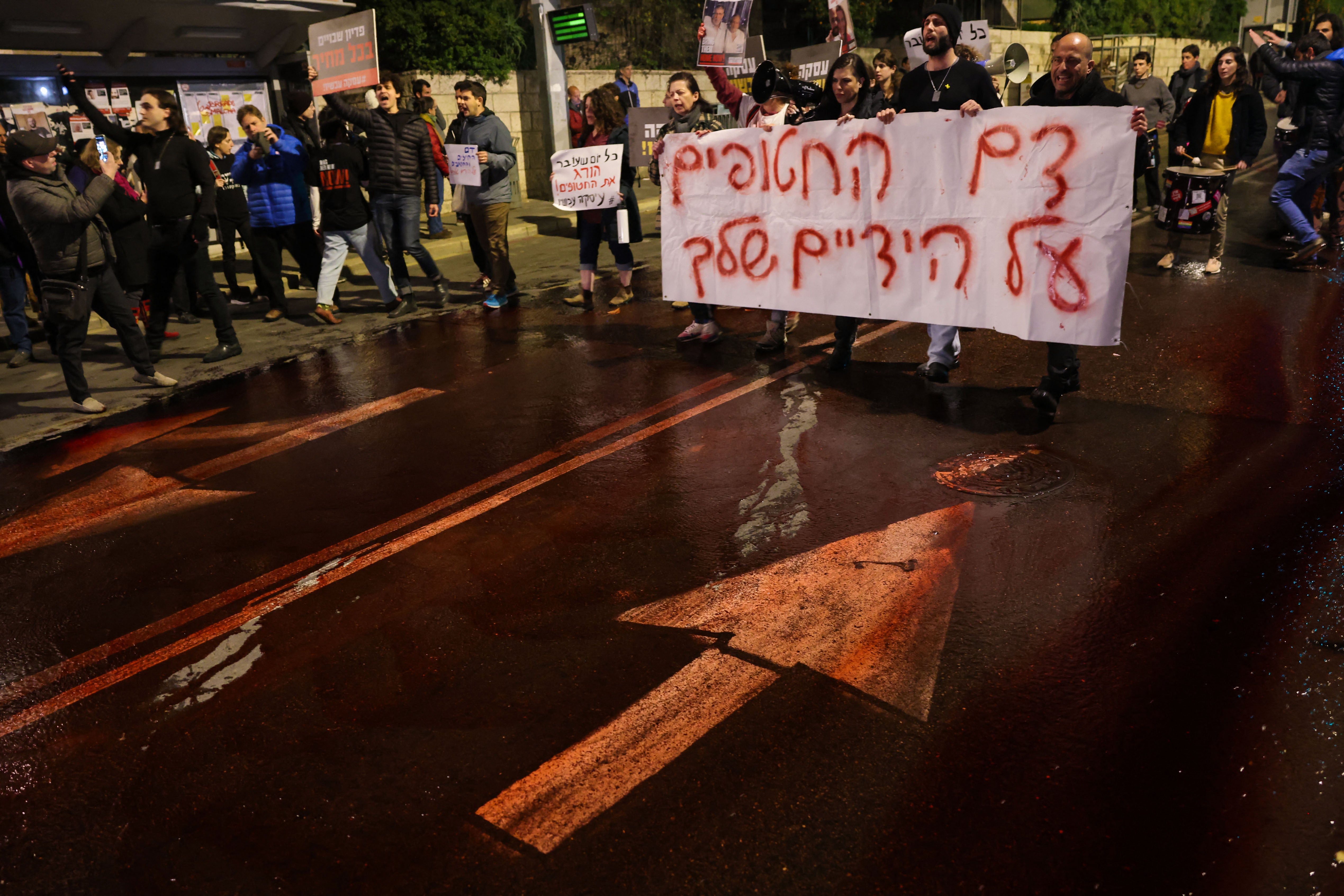 Protesters spill red paint on the road to symbolise the blood of the Israeli hostages held in Gaza since the 7 October attacks