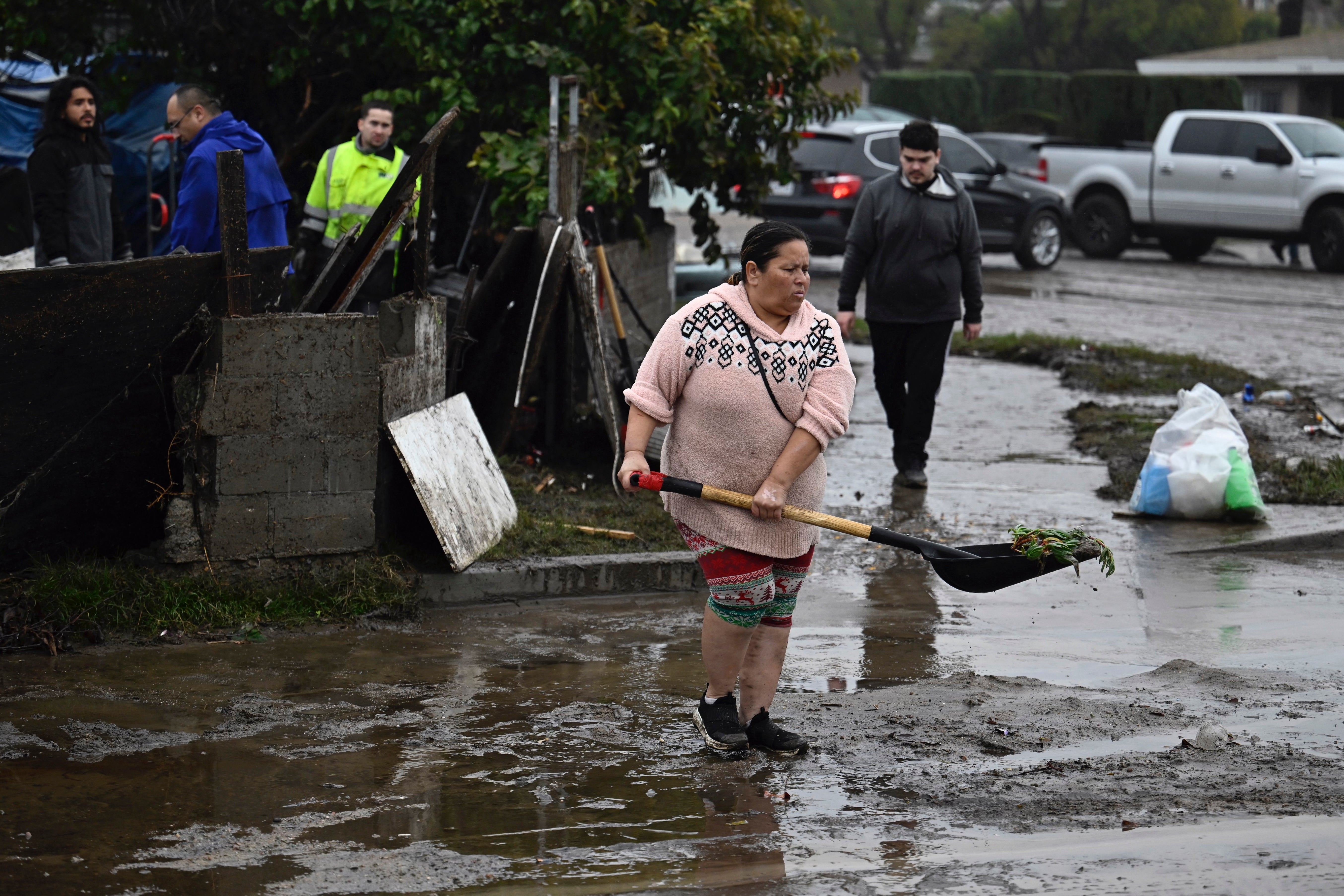 A woman removes debris from floods on Monday