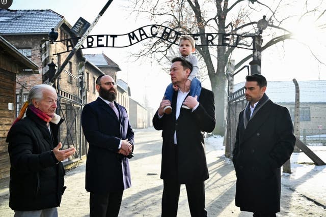 <p>Musk carries his son on his shoulders at Auschwitz, just metres from where thousands of Jewish prisoners were murdered </p>