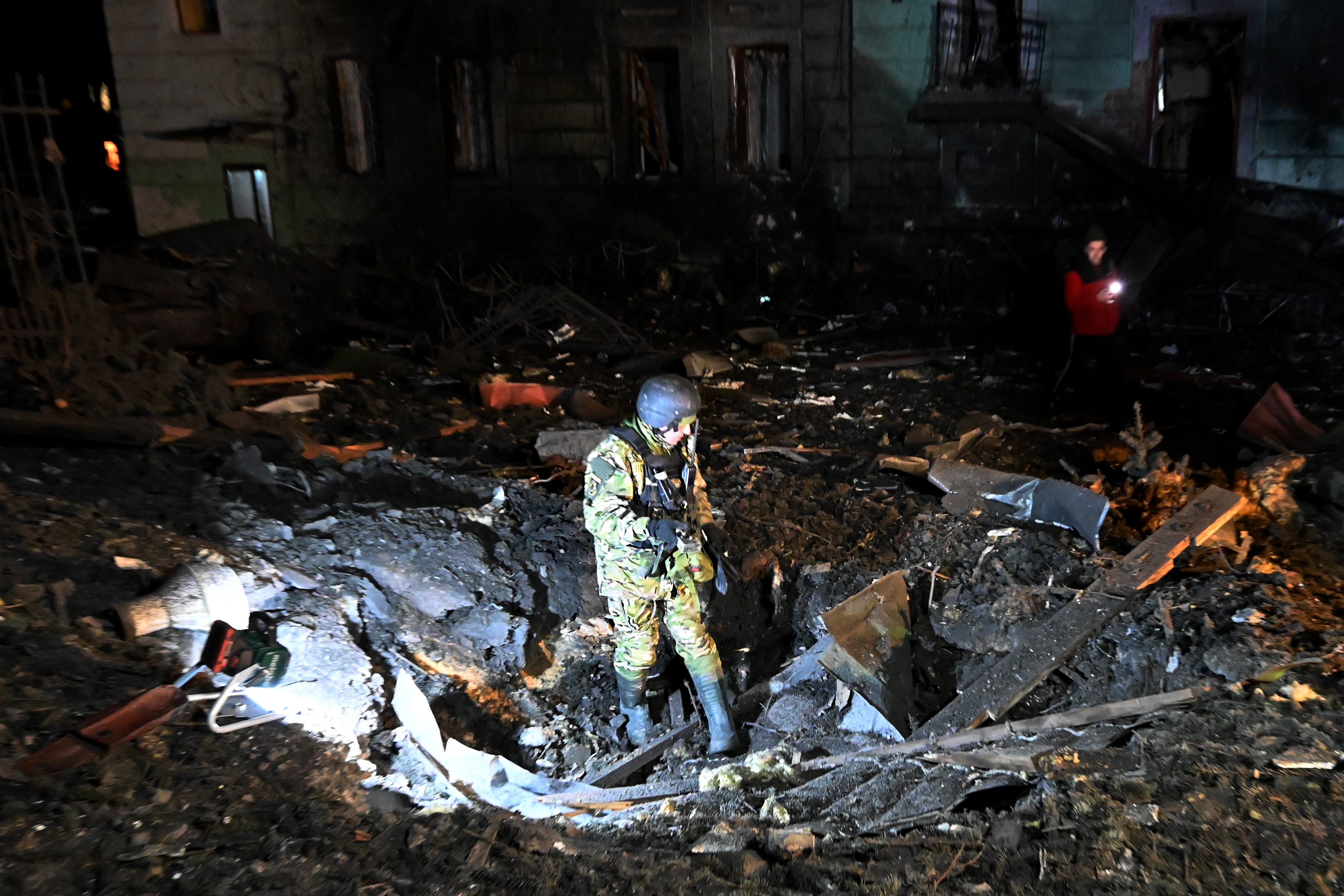 An explosives expert inspects a crater following a missile attack in Kharkiv